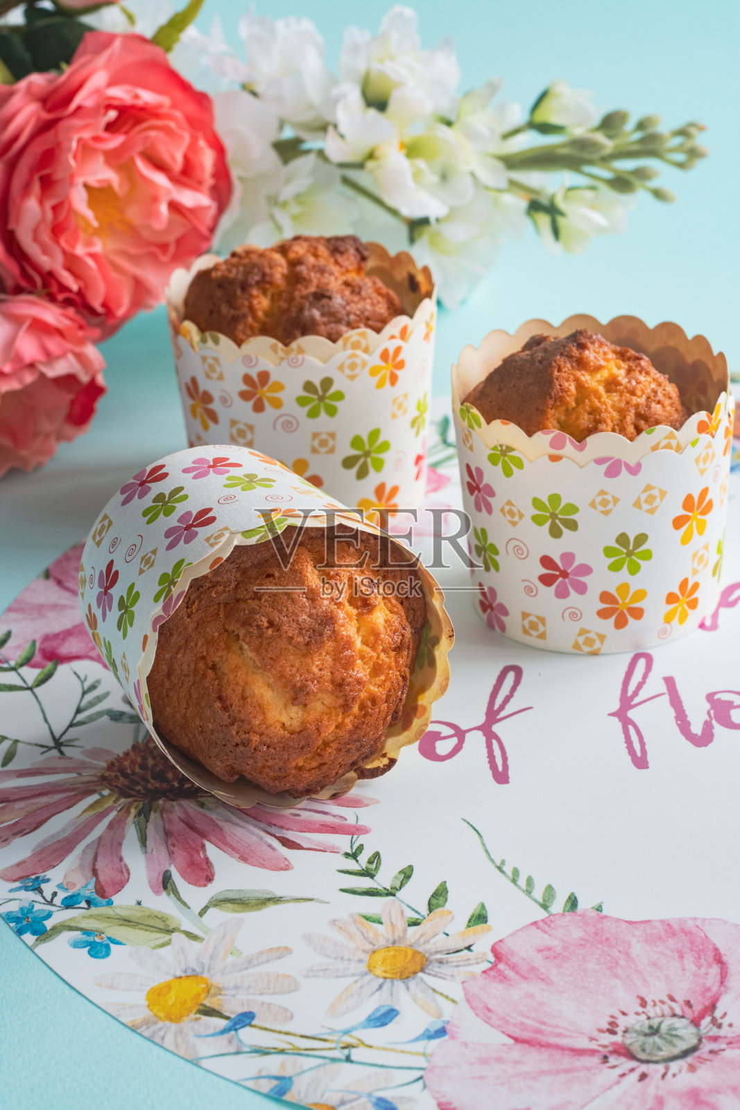 三个松饼，浅蓝色的背景上装饰着花朵照片摄影图片