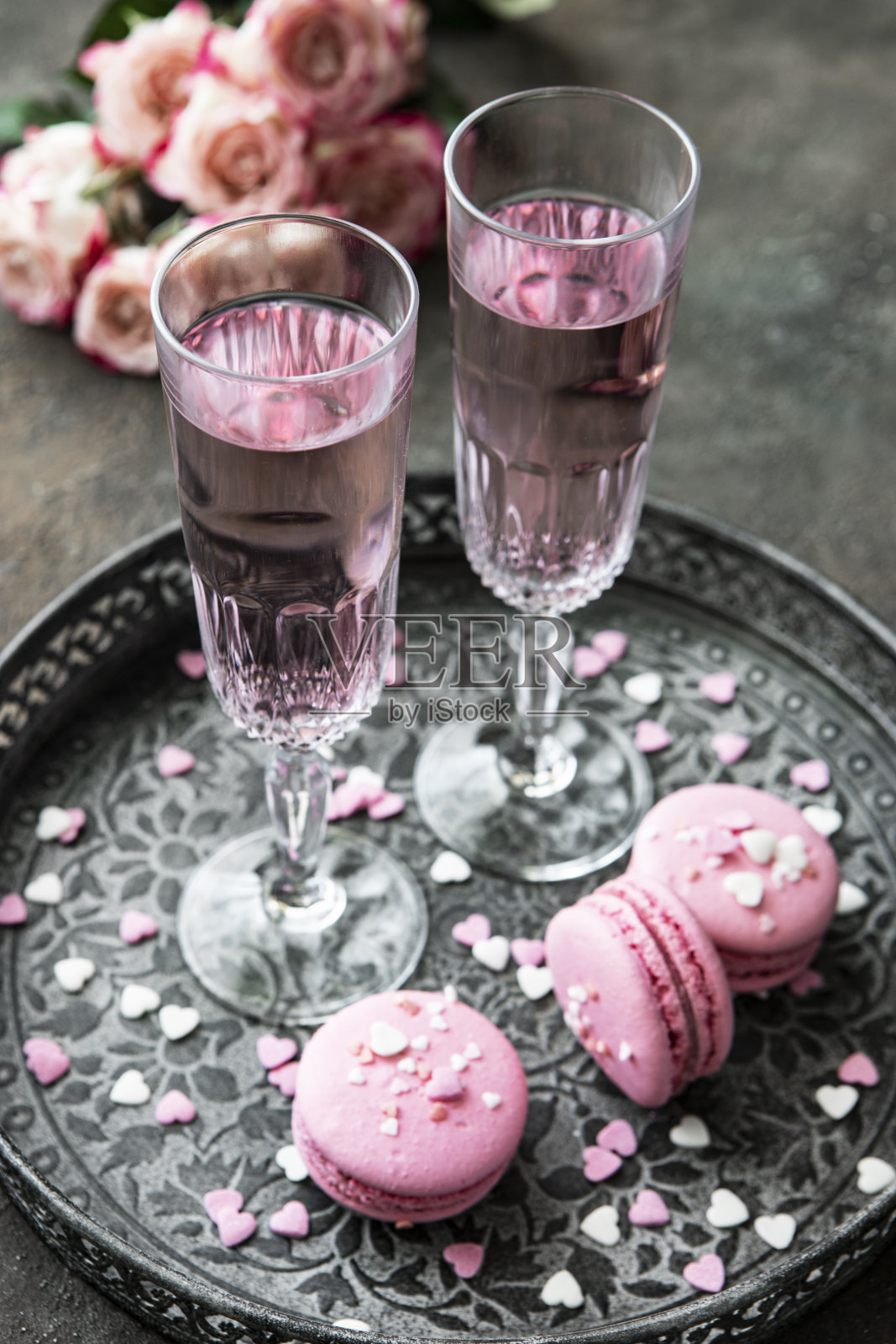 两个叮当作响的香槟杯与玫瑰花束的颜色背景照片摄影图片