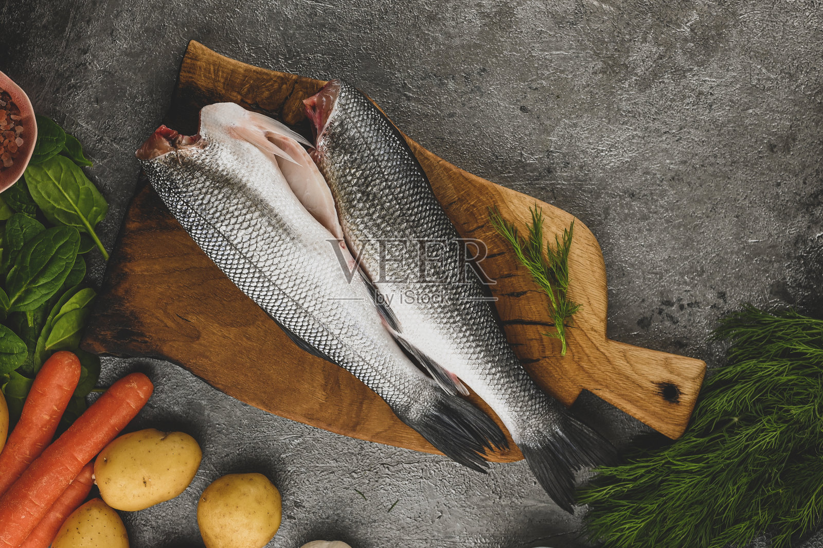 鱼烹饪准备。健康的减肥食品。鲈鱼配以新鲜有机食材，为您烹制美味佳肴。前视图。仍然生活。照片摄影图片