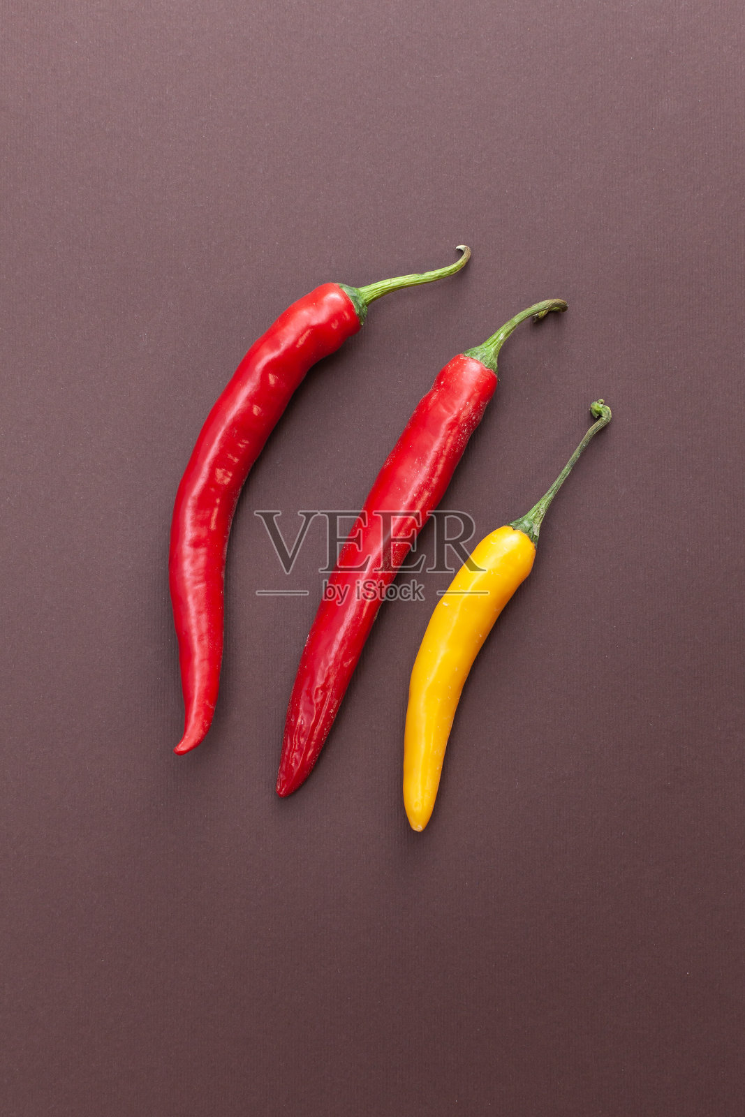 红色和黄色的胡椒分离在棕色背景上照片摄影图片