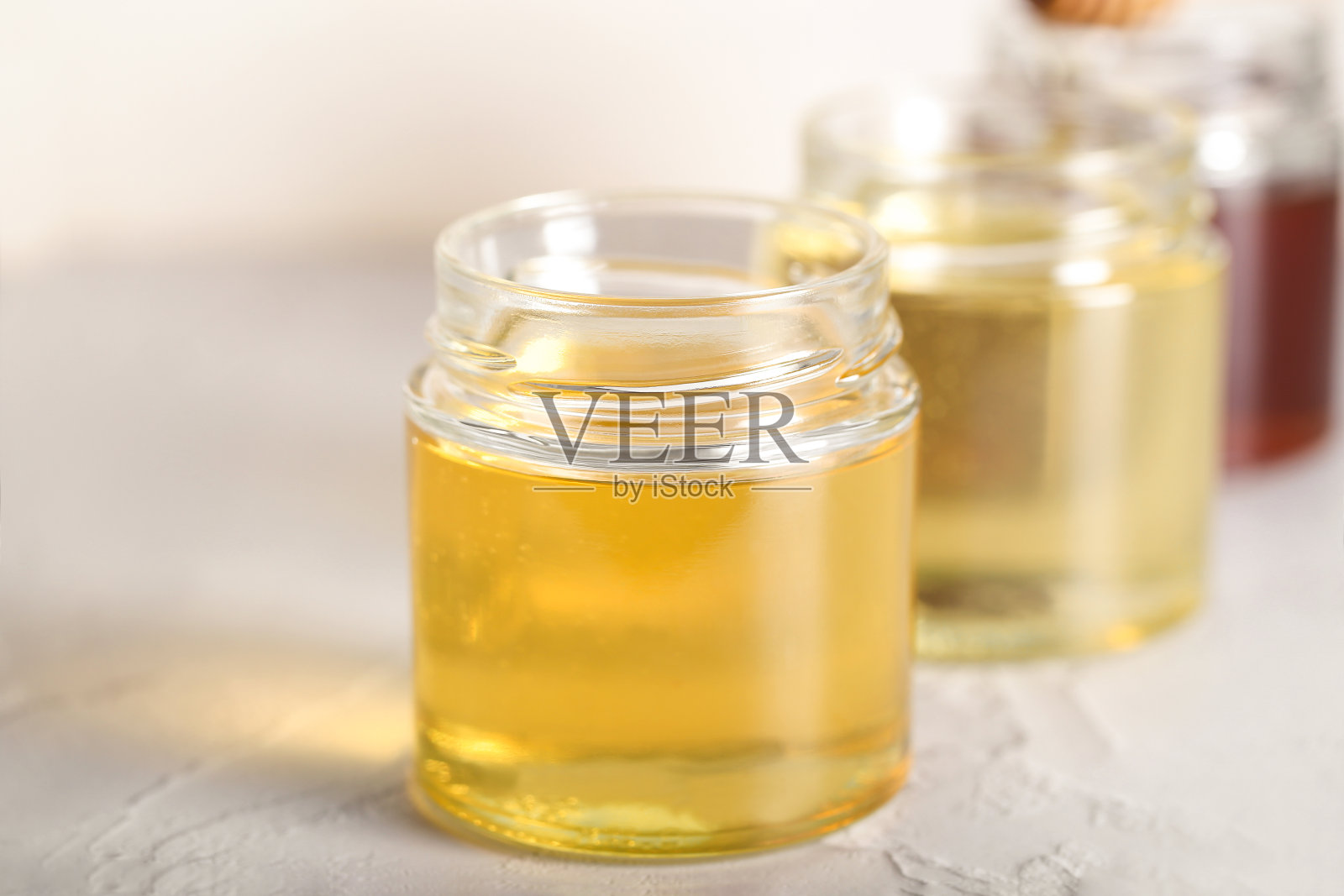 桌上的玻璃罐里放着各种各样的蜂蜜照片摄影图片