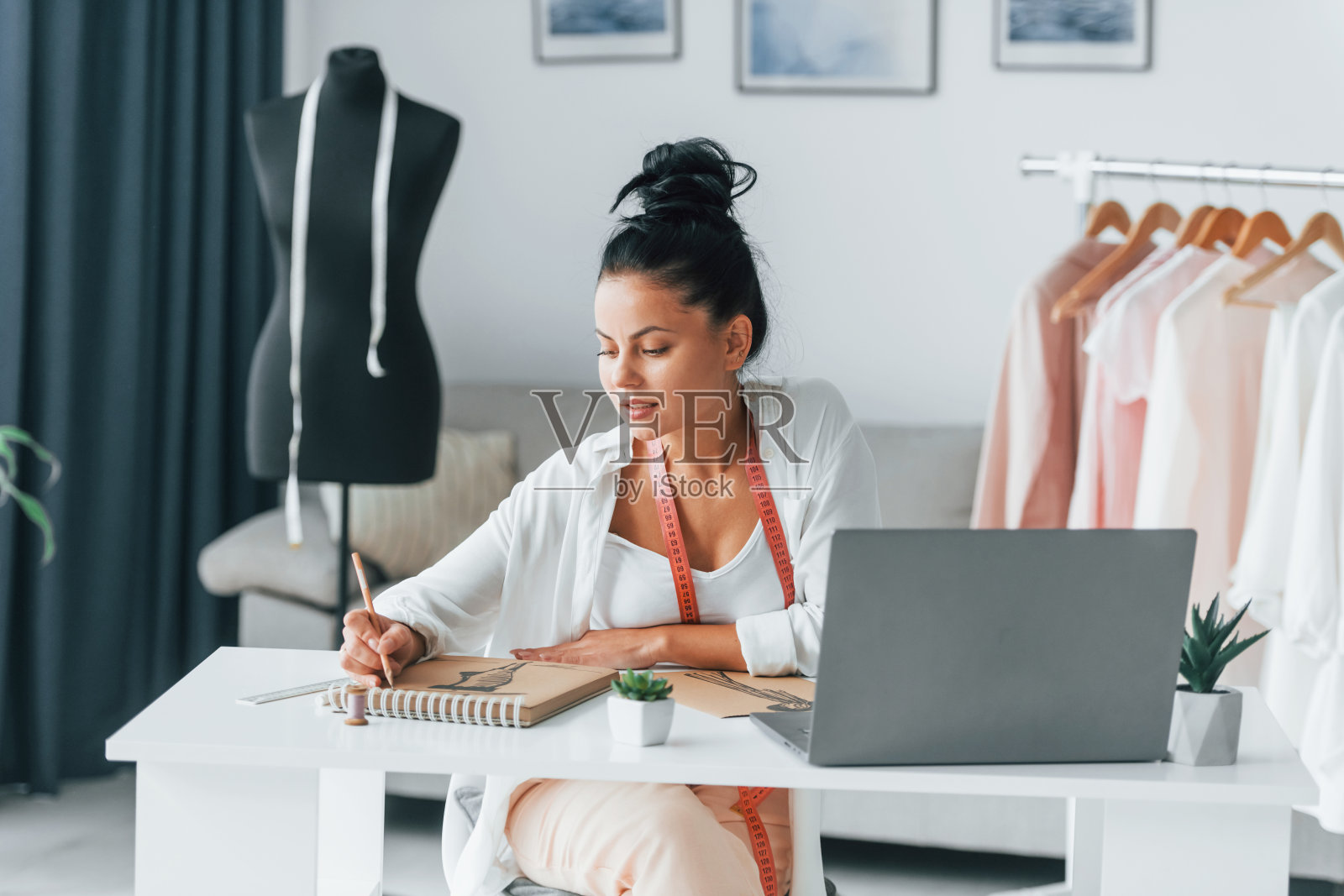 忙碌的一天。女裁缝在她的办公室里穿着不同的衣服照片摄影图片