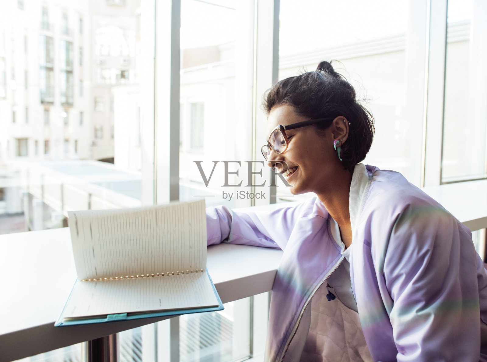 年轻可爱的潮女学生坐在咖啡馆里拿着笔记本看书，戴着眼镜，生活方式快乐微笑的人的概念近距离接近照片摄影图片