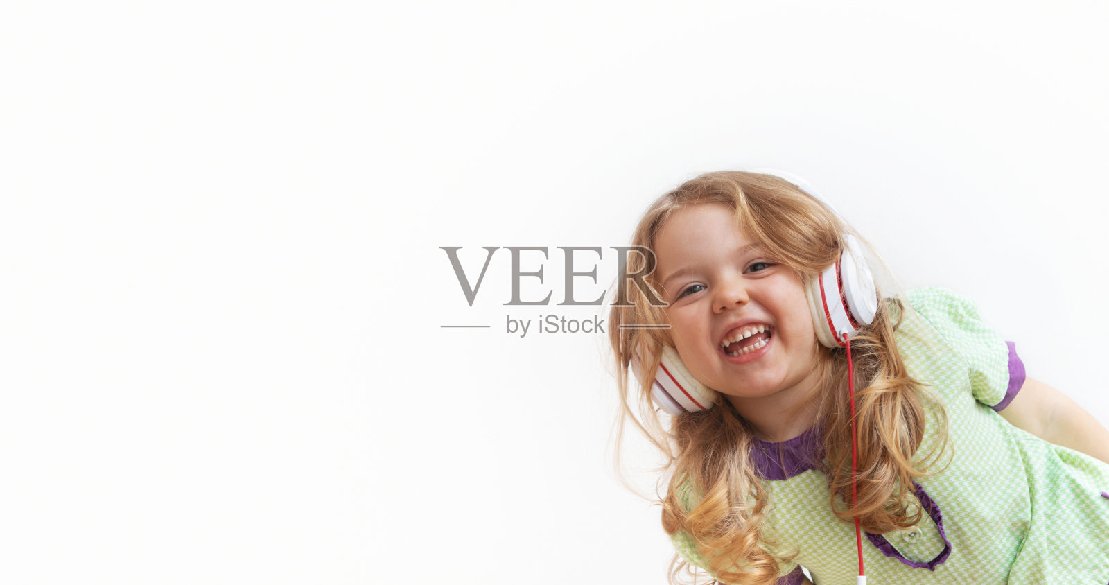 愉快有趣的小女孩戴着白色背景的耳机。在线音乐或娱乐。带有复制空间的横幅照片摄影图片