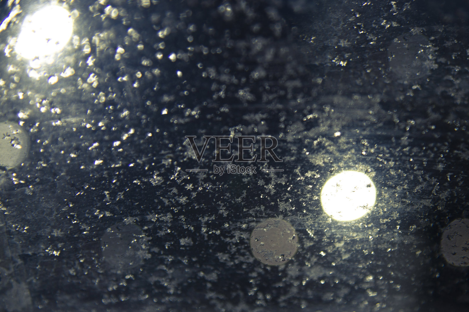 模糊的抽象深蓝色背景与发光的圆圈和雪花。照片摄影图片