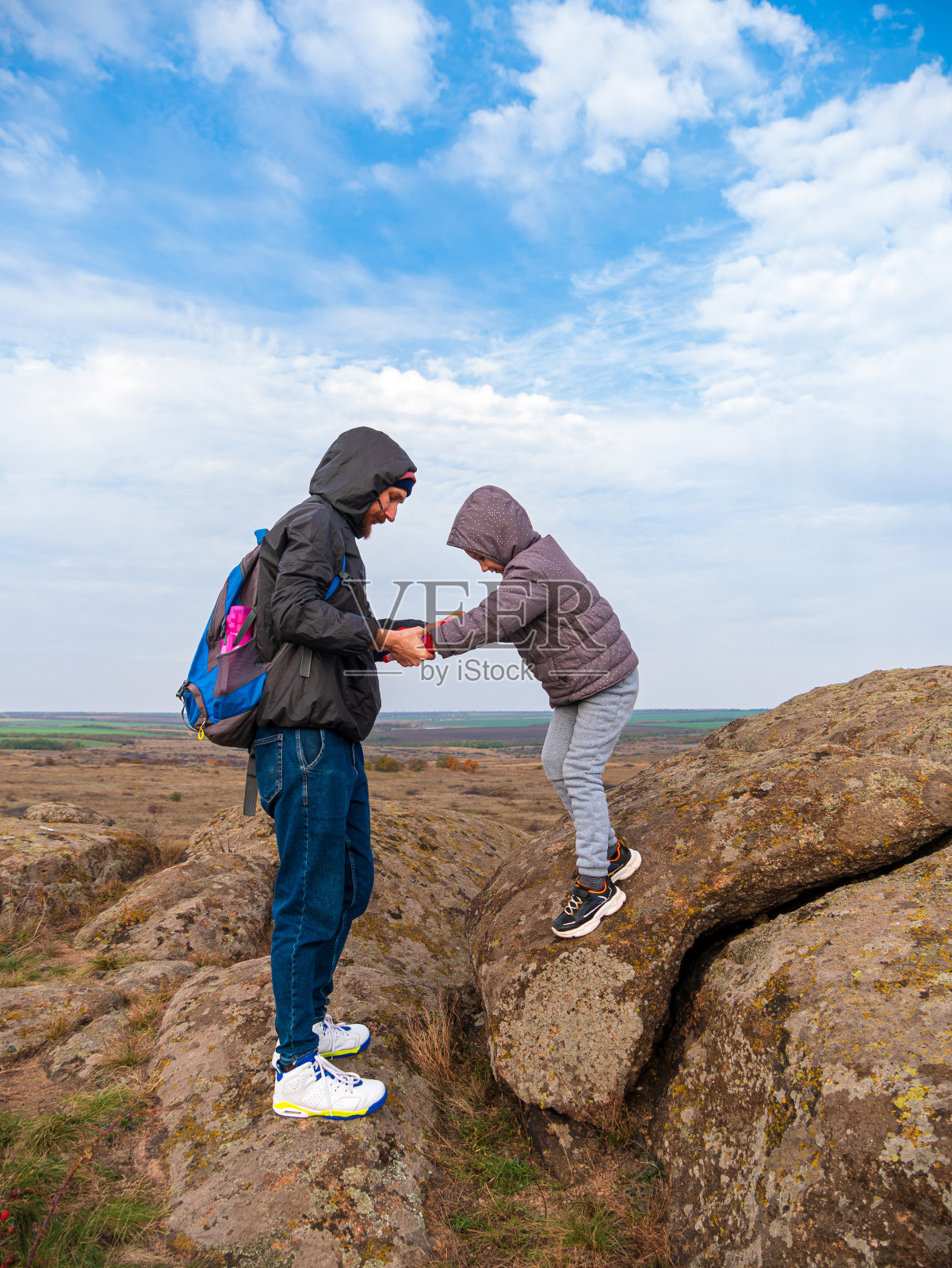 游客父女俩徒步爬山，一起鸟瞰蓝天多云的背影。照片摄影图片