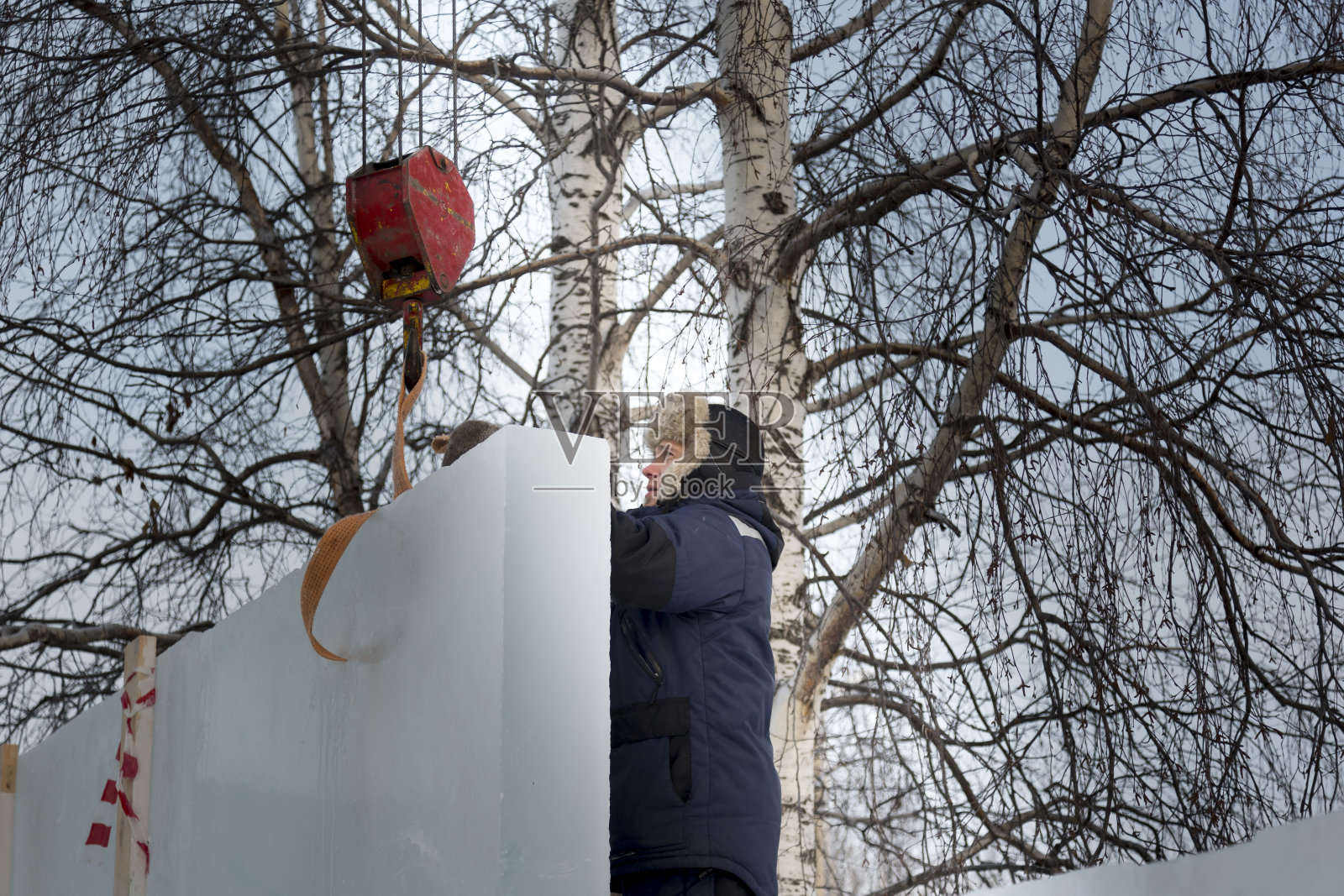 工地上身穿蓝色夹克、头戴皮帽的装配工人照片摄影图片