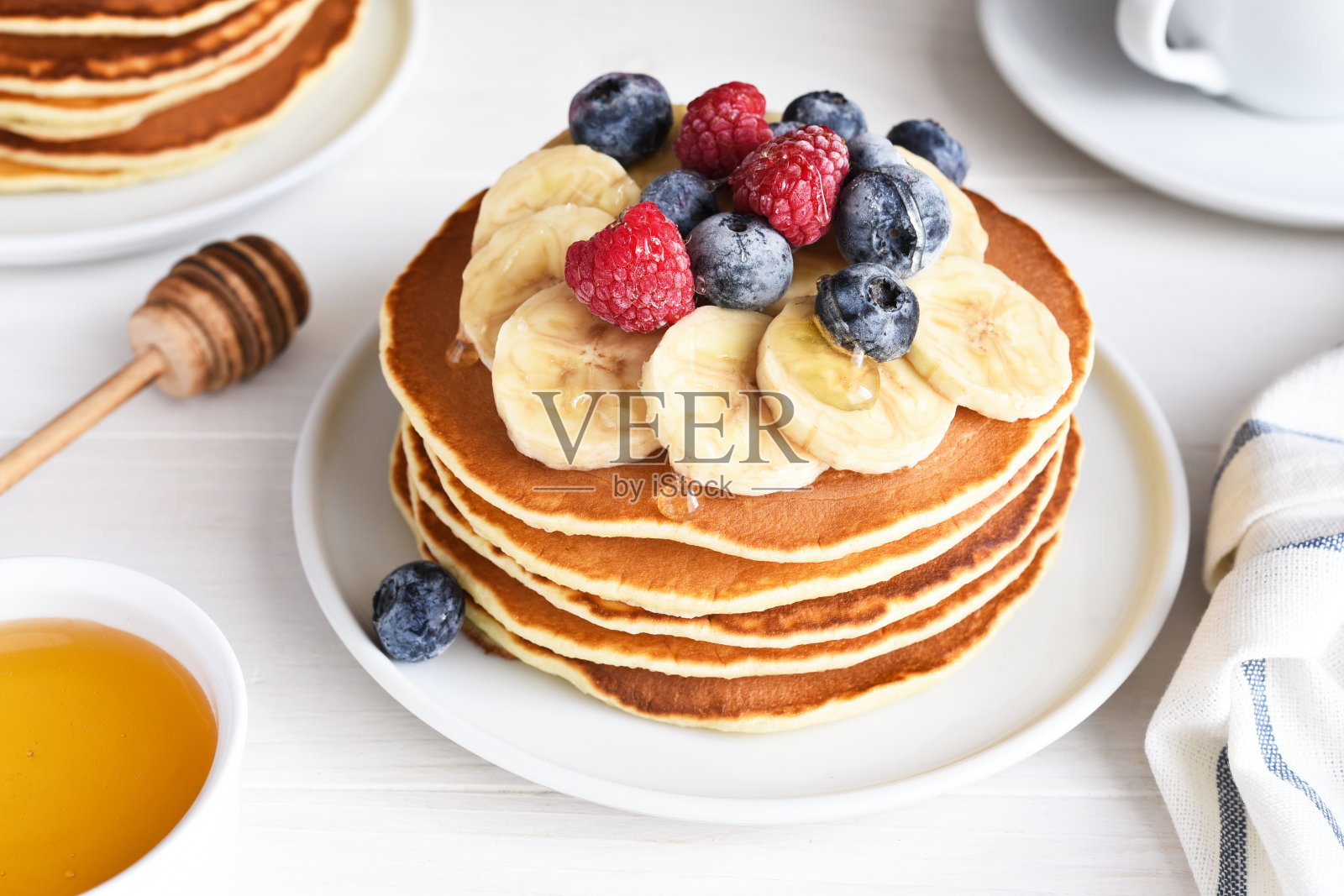 厨房桌上的早餐是一堆煎饼、浆果和糖浆。早上好照片摄影图片