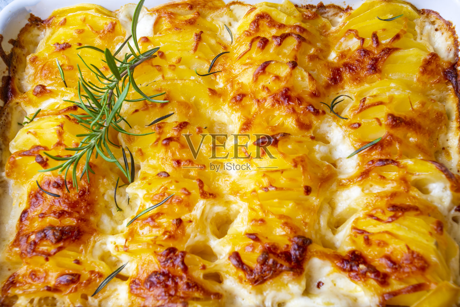 烤土豆——烤土豆配奶油和奶酪，配迷迭香和叉子(土耳其名字;Kremali patates)照片摄影图片