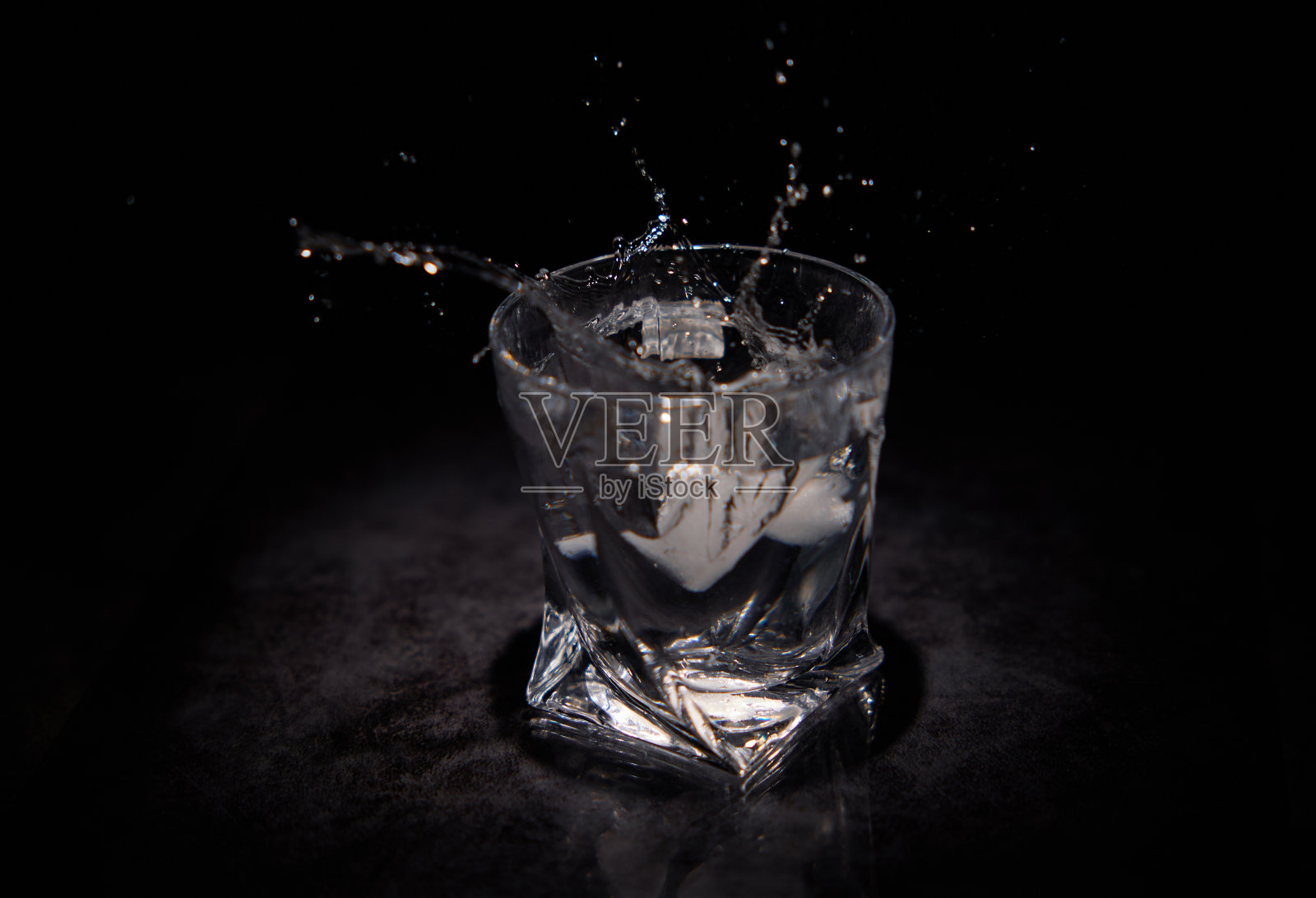 飞溅的水从一块冰落到透明的照片摄影图片