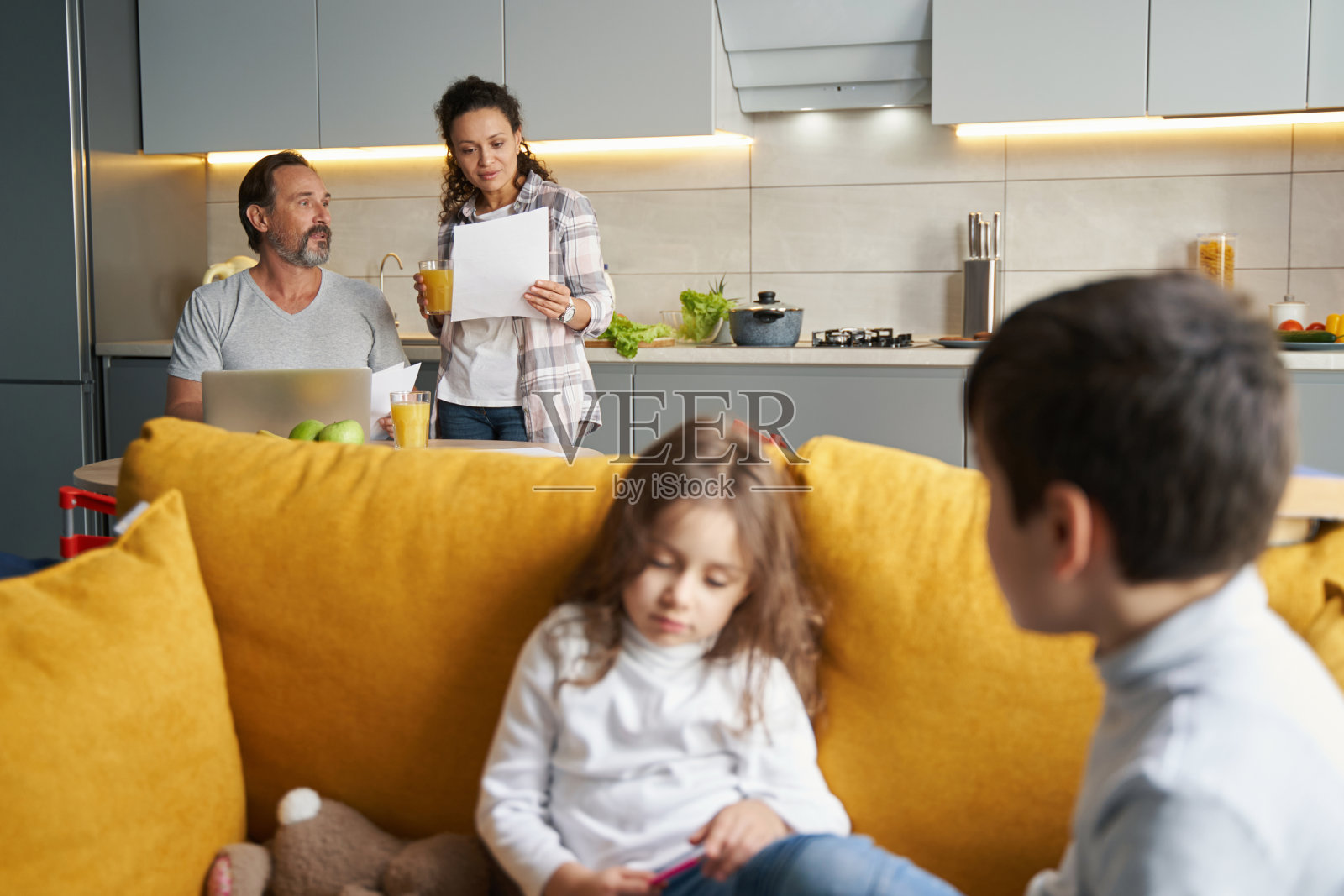 女人在丈夫身边检查报纸，孩子在沙发上照片摄影图片