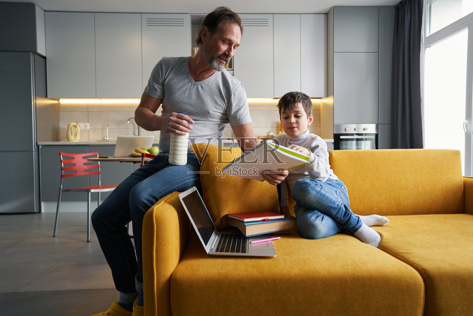 父母坐在沙发边，辅导孩子做作业照片摄影图片