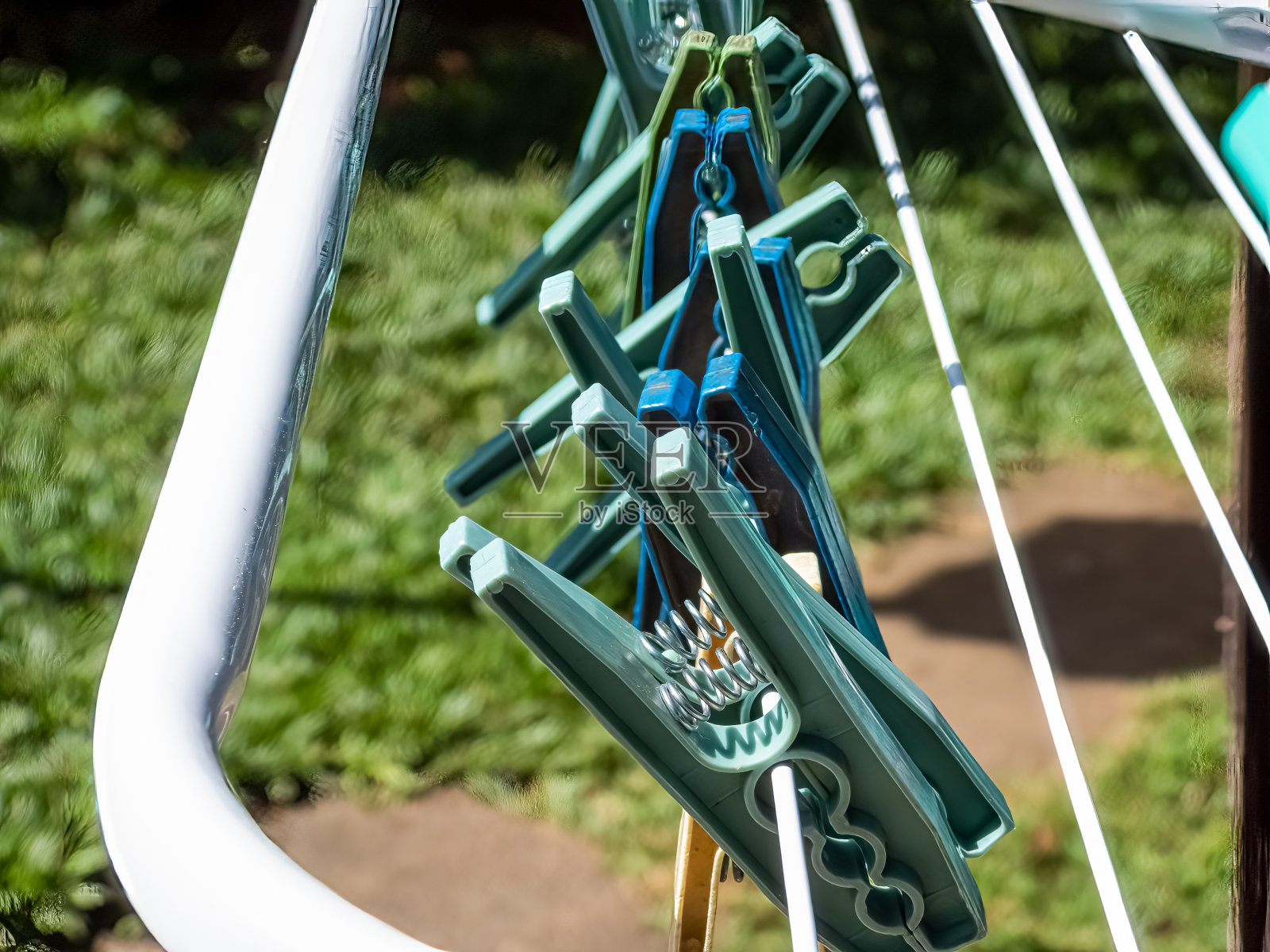 绿色和蓝色的晒衣夹在白色的金属晒衣绳上照片摄影图片