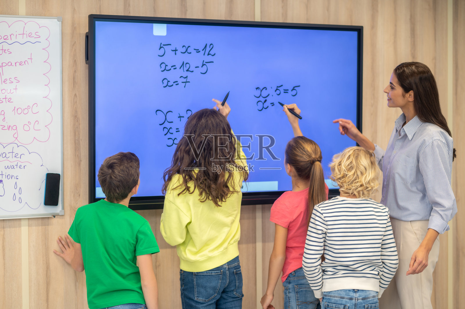 孩子和老师站在黑板旁边的背影照片摄影图片