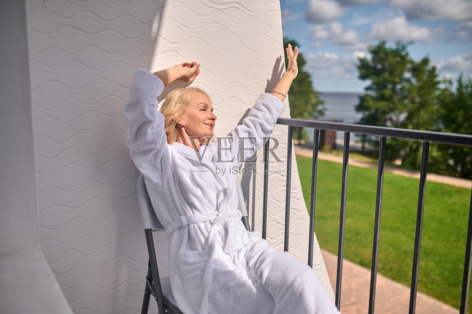 一个金发的中年妇女在一个阳光明媚的日子里穿着白袍照片摄影图片