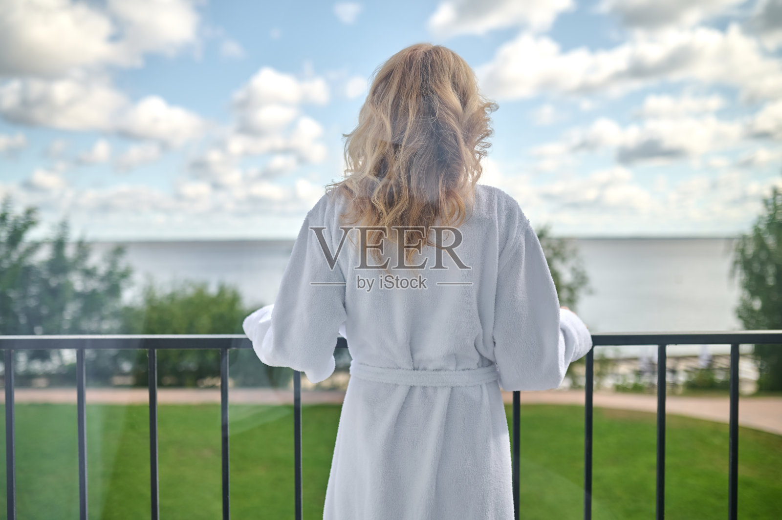 一个穿着白袍的金发女人站在阳台上照片摄影图片