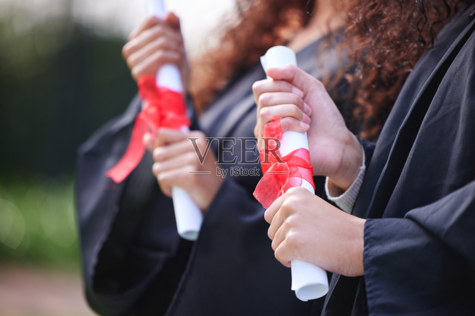 近距离拍摄的两个不认识的学生拿着他们的毕业证书在毕业日照片摄影图片