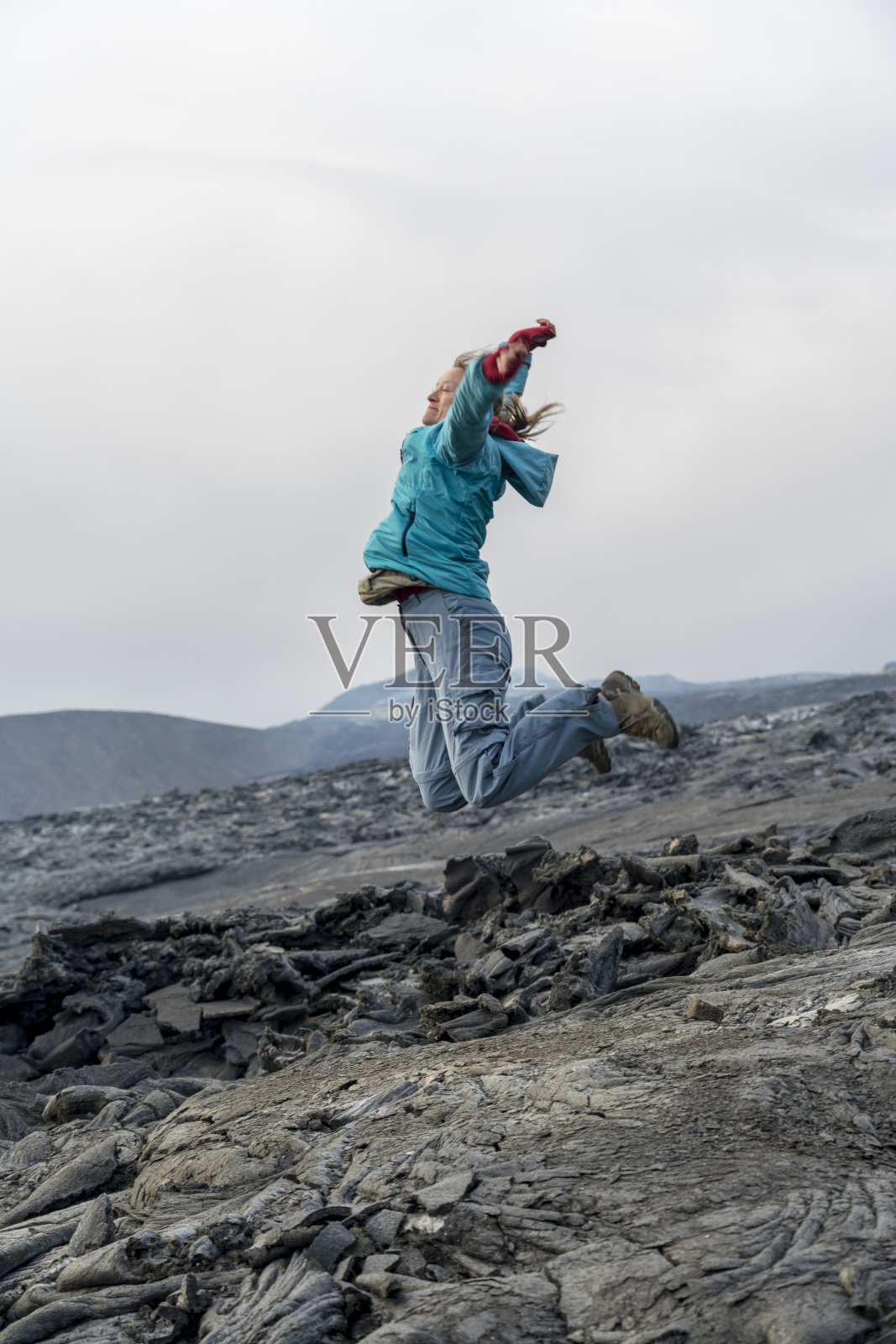 女人们在Fagradalsfjall火山的黑色熔岩上跳跃照片摄影图片