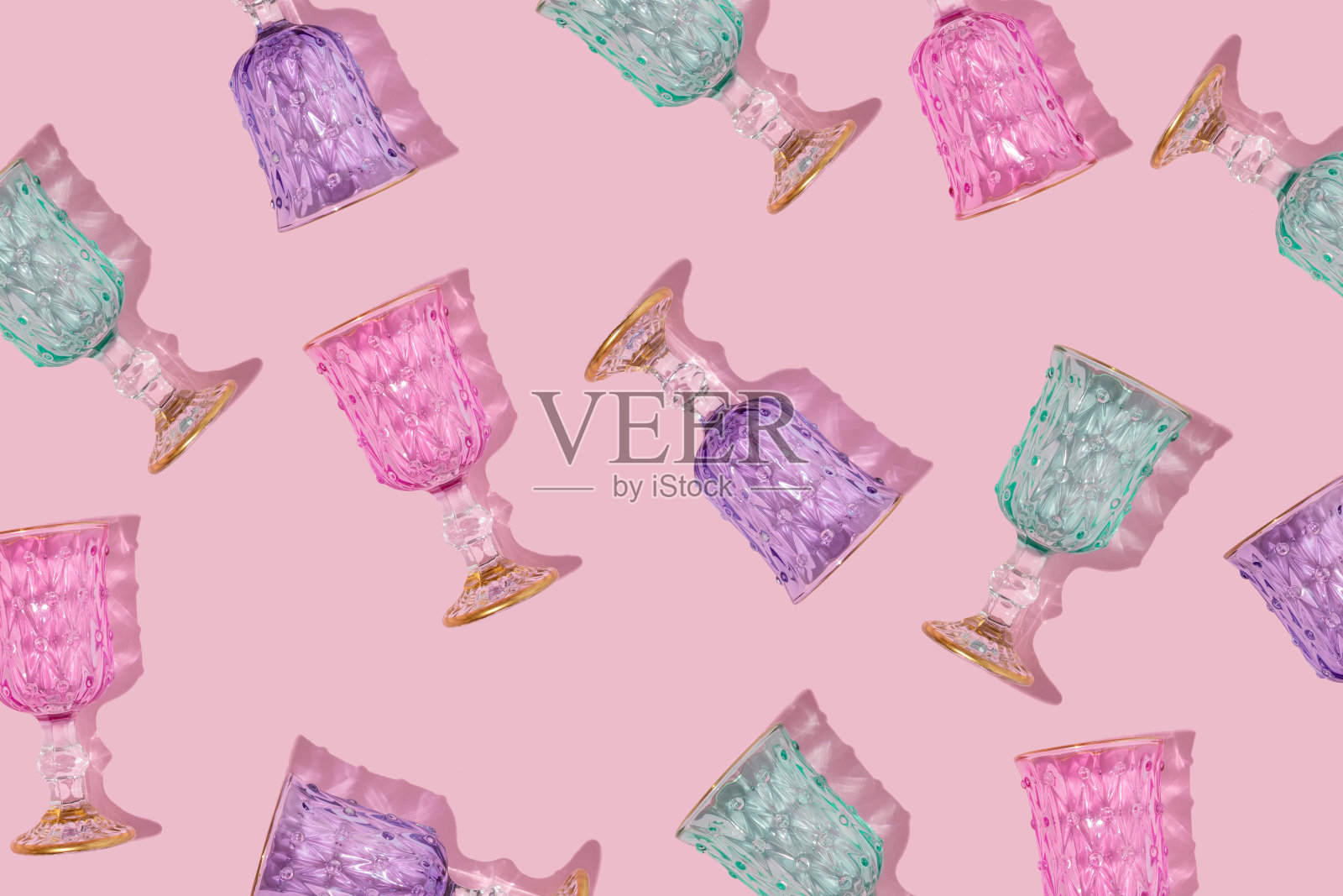 创意图案与彩色香槟酒杯在柔和的粉红色背景。庆祝审美观念。乐观时尚的生活理念。照片摄影图片