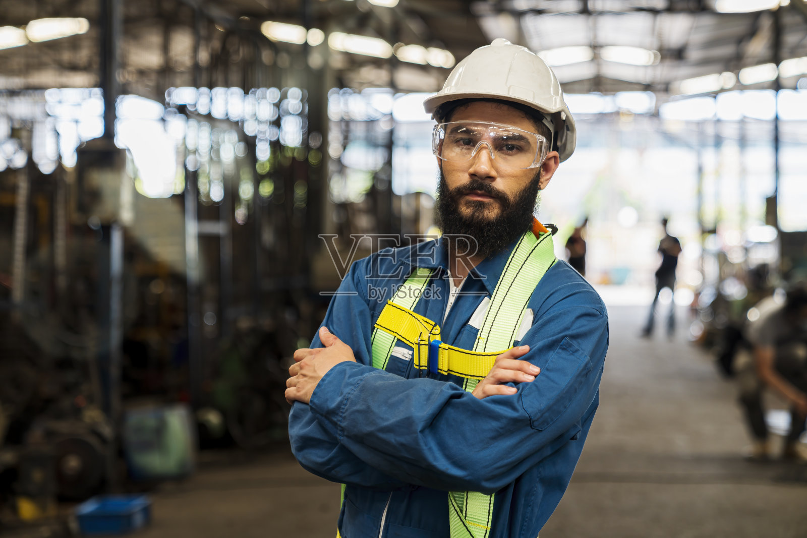 工程师和熟练的技术人员正在维护机器。工程师们在工业上工作和修理机器。工人微笑着站在工厂附近，双臂交叉。照片摄影图片