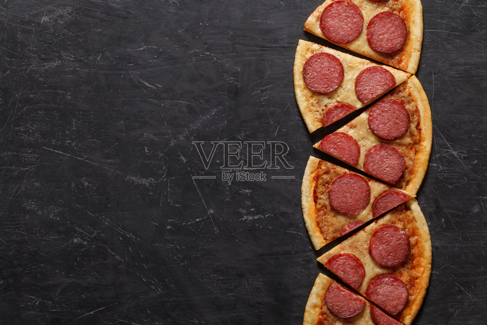 意大利辣香肠披萨，切成六块，排成一行，俯视图黑色背景，有空间复制文本。照片摄影图片