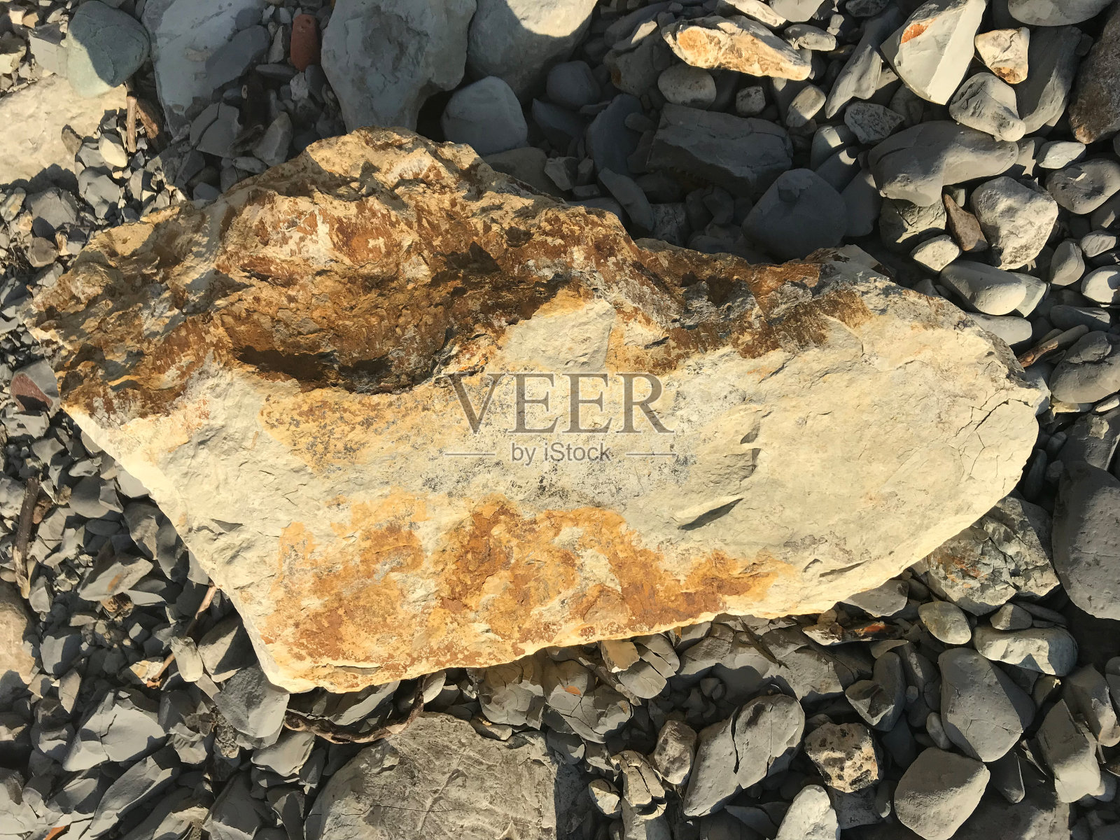 一块大石头躺在沙滩上的一块卵石上。块的岩石照片摄影图片