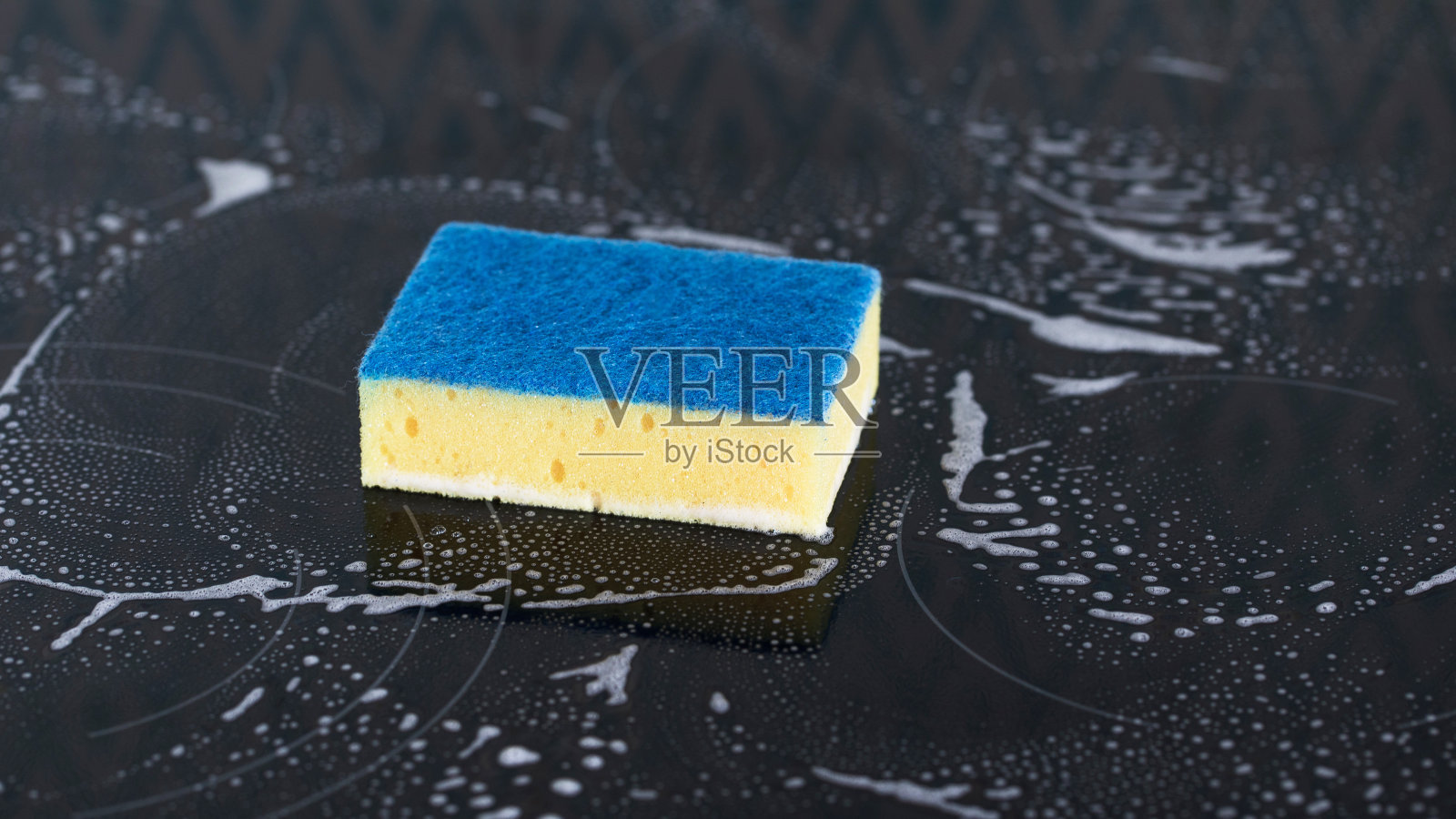 炉子上的黄色海绵泡在泡沫里。大扫除的概念。照片摄影图片