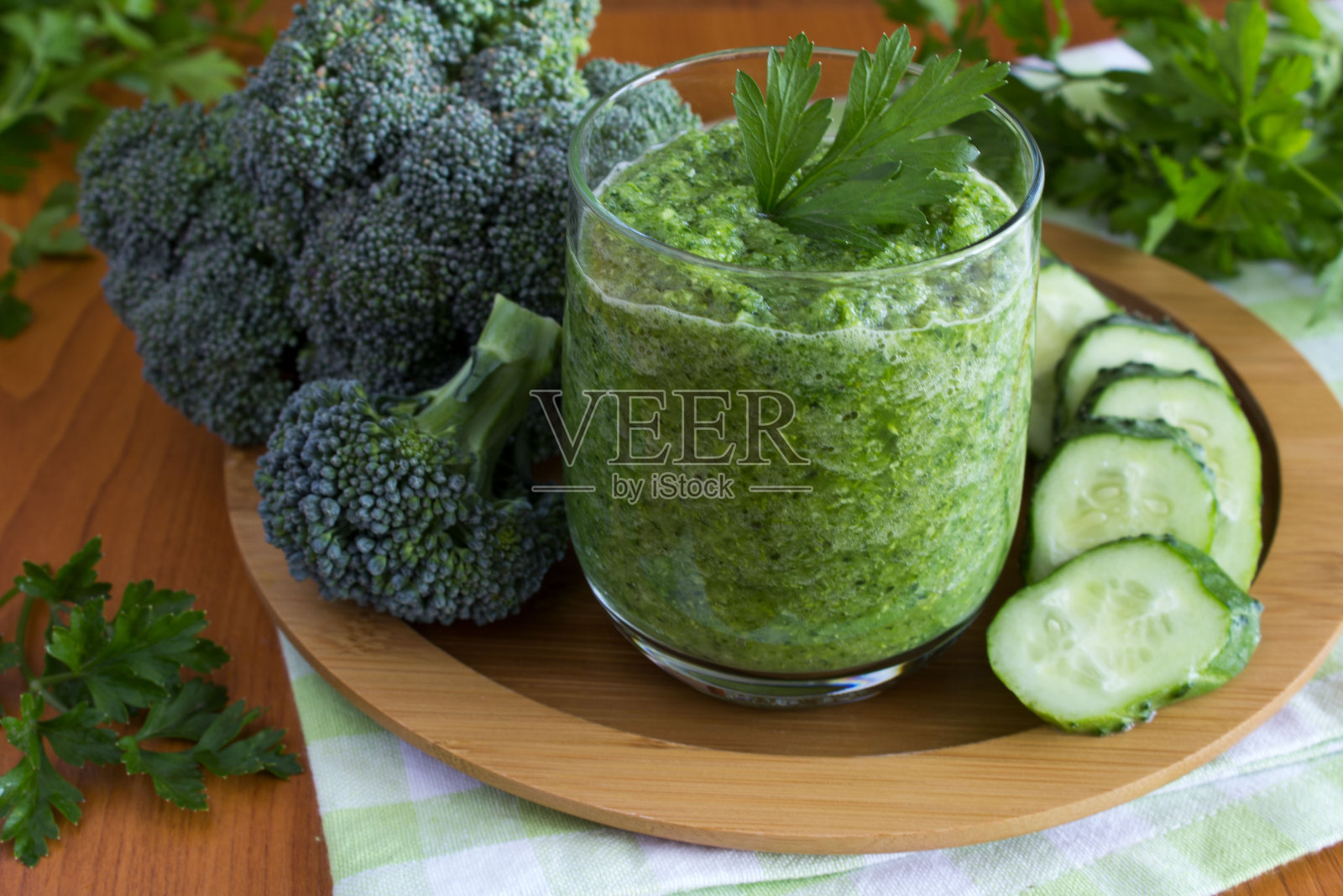 切菜板上的水杯里盛着黄瓜和西兰花的奶昔。特写镜头。照片摄影图片