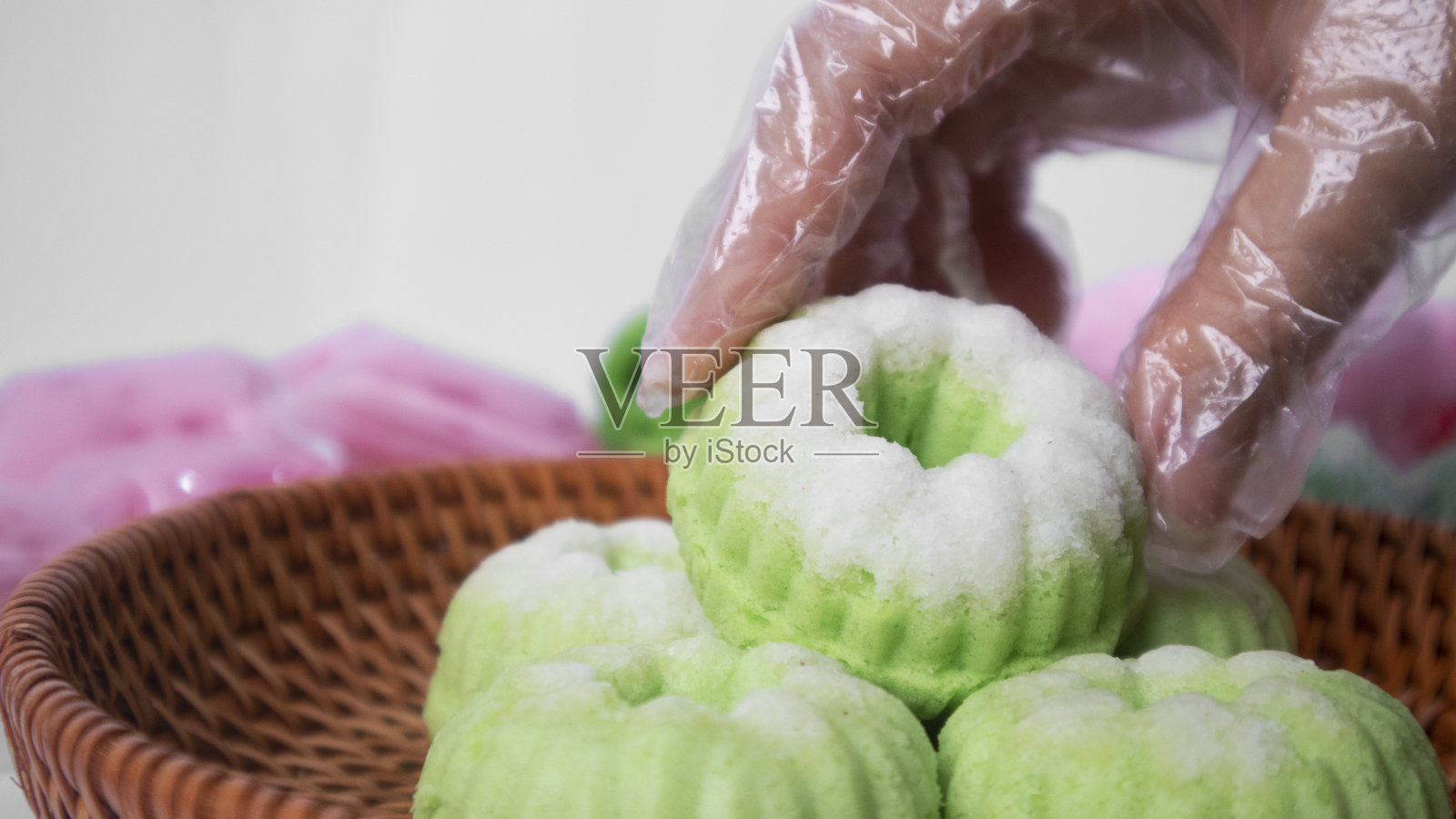 一只手拿起一个印尼椰子蒸香兰饼照片摄影图片