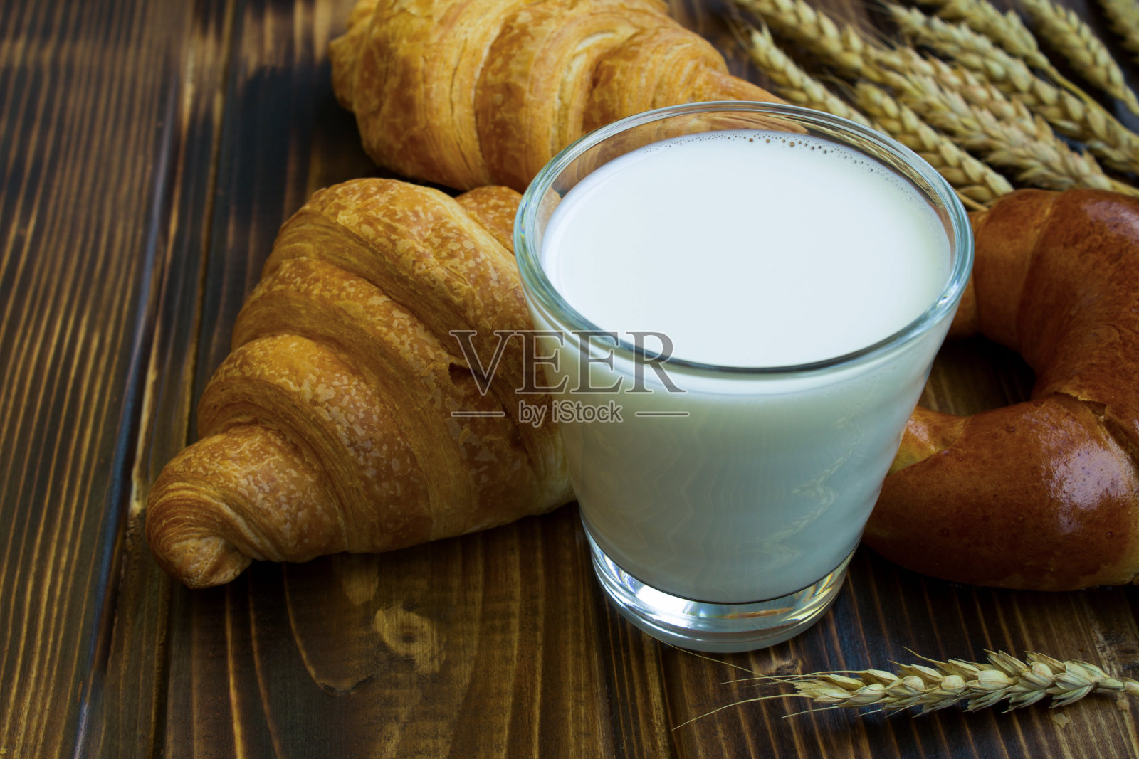 牛奶在饮料杯和烘焙产品在木制背景。特写镜头。照片摄影图片