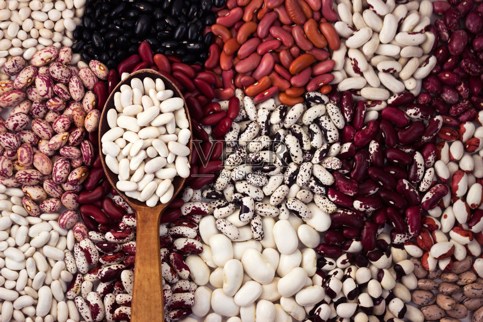 不同类型的豆子，背景。大量的白色，红色，黑色和彩色的豆子，背景。木勺配白豆照片摄影图片