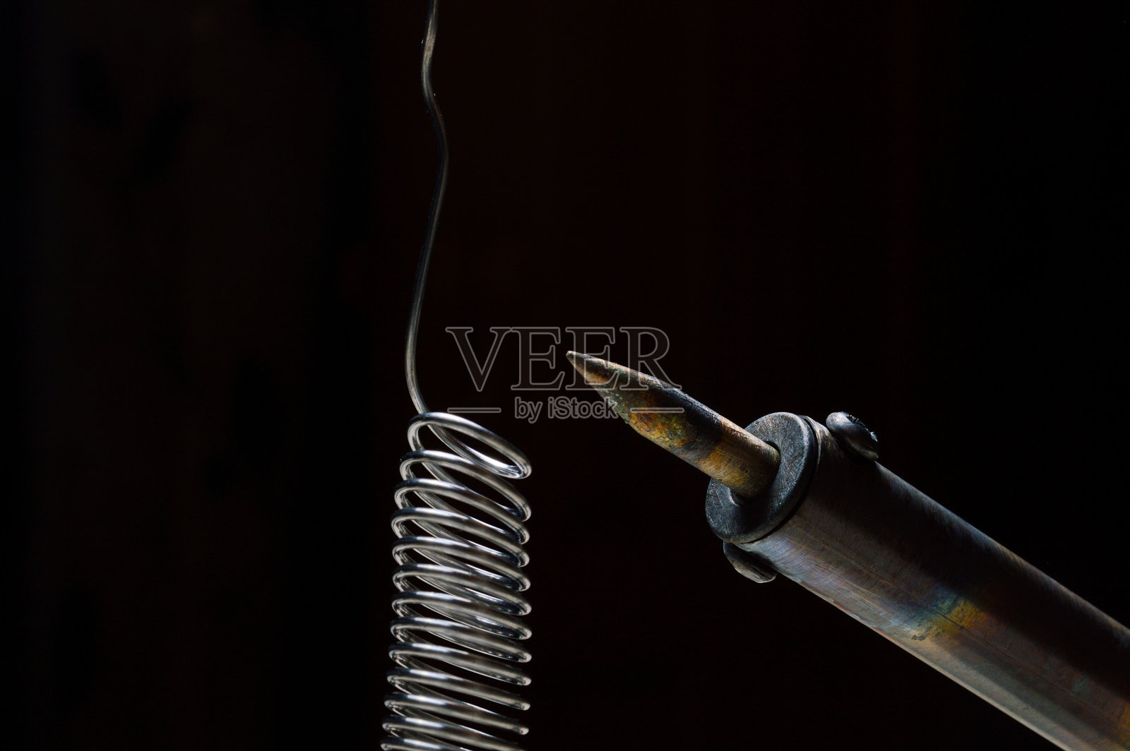 加热烙铁和焊料。黑暗的背景。特写镜头。照片摄影图片