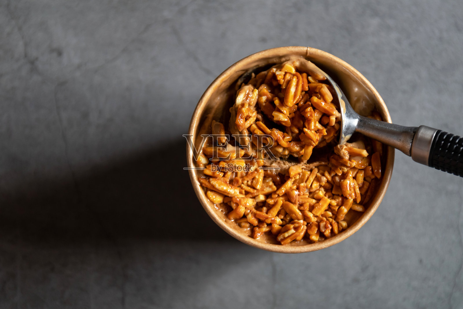 桶容器的咖啡杏仁冰淇淋与充分的杏仁在上面孤立的灰色背景。照片摄影图片