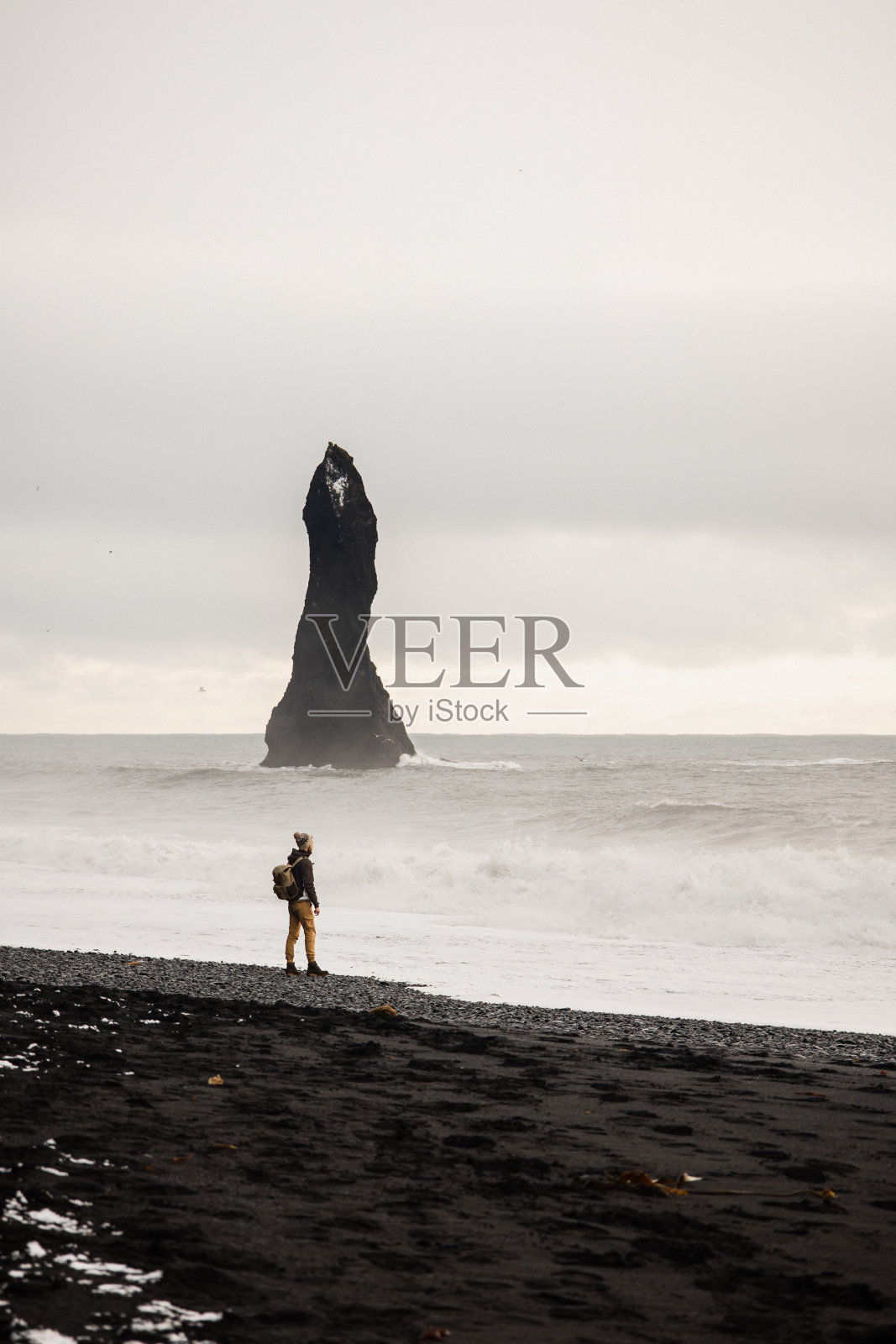 一名年轻人在冬天欣赏Reynisfjara黑沙滩上的景色照片摄影图片