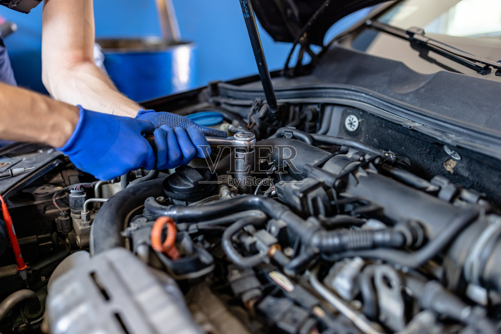 年轻的男性汽车修理工正在和机械师一起解决汽车发动机的问题。照片摄影图片