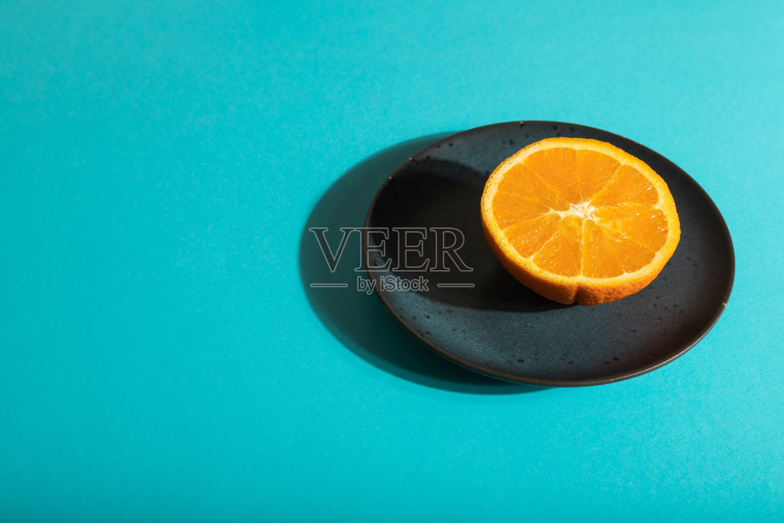 成熟切橙色在蓝色陶瓷板上蓝色柔和的背景。侧视图，复制空间，强光。照片摄影图片