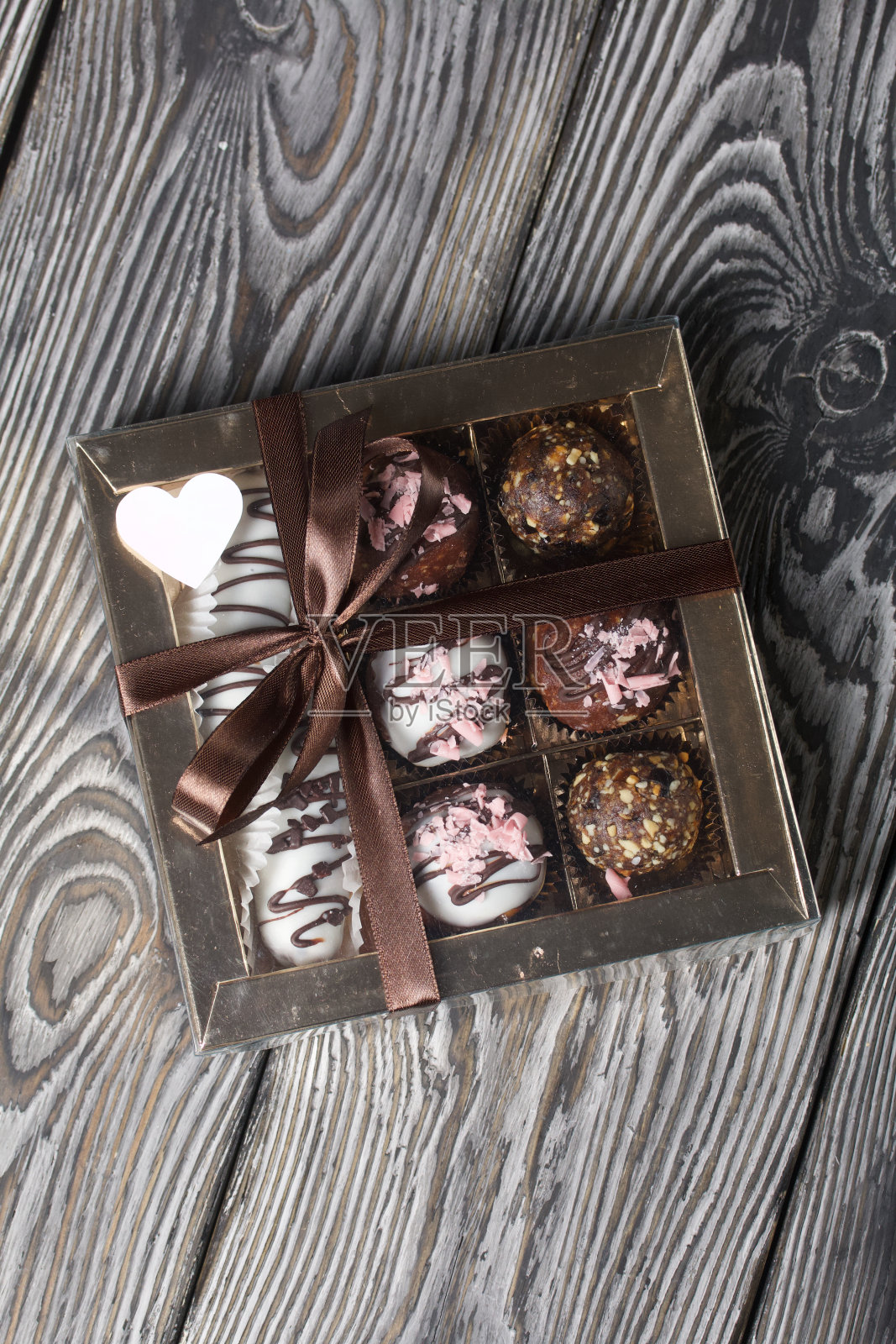 巧克力糖。在礼品盒里。用丝带系成一个蝴蝶结。松木板。照片摄影图片