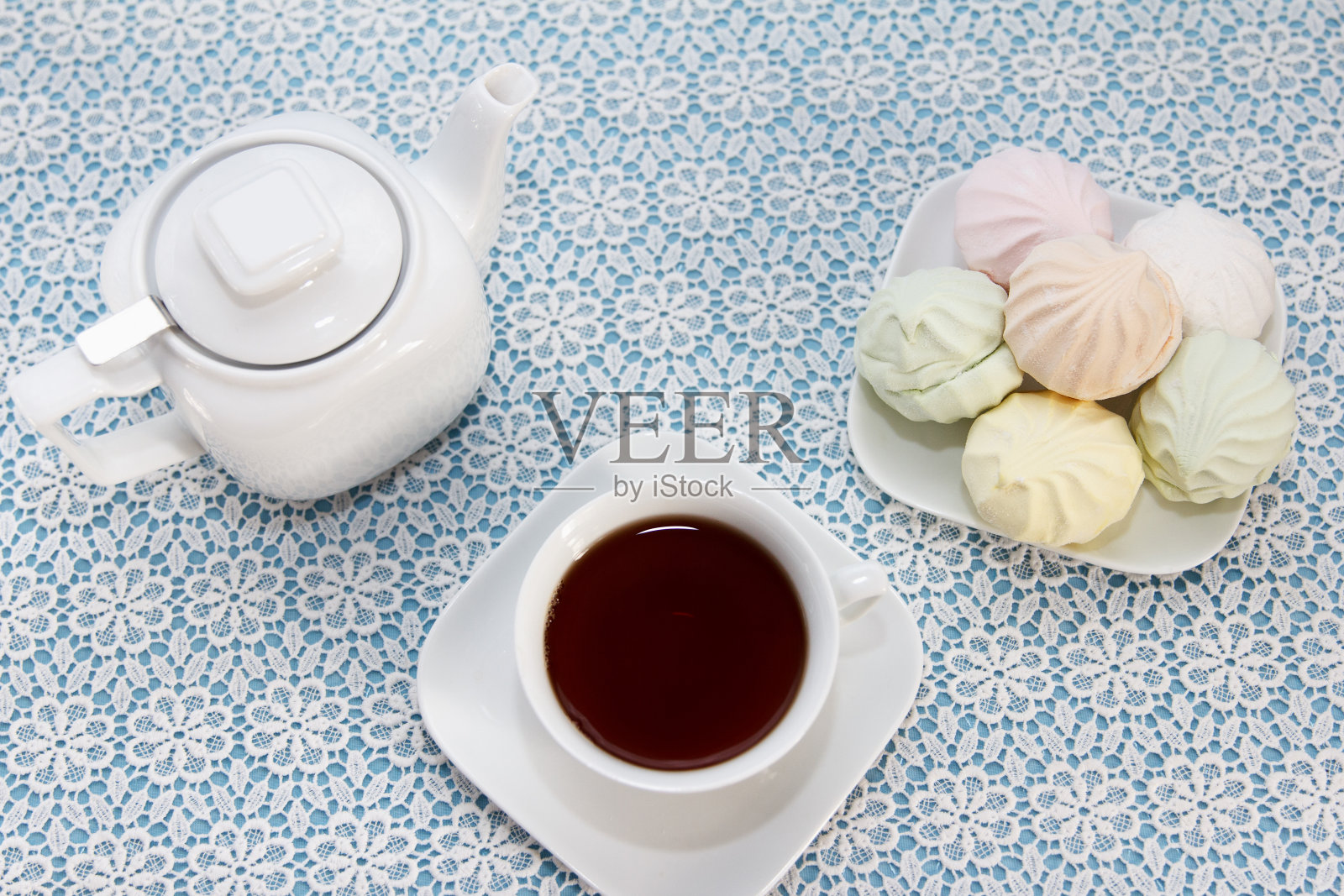 用茶杯、茶壶冲泡的传统茶和放在桌子上的空棉花糖，这是一道甜点照片摄影图片