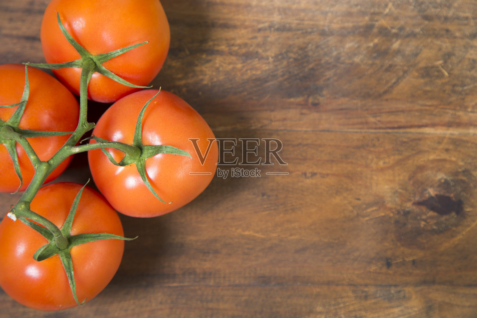 一簇新鲜的西红柿放在木制的桌面上。素食照片摄影图片