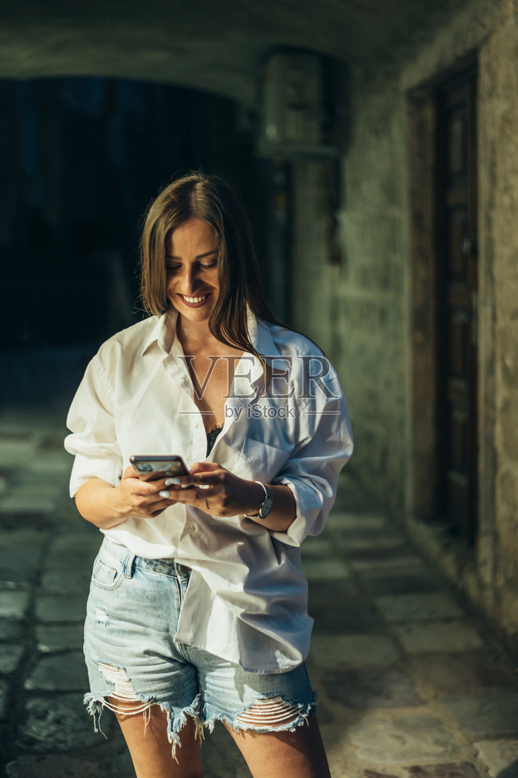 美丽的年轻女子使用智能手机行走在城市街道上的海岸在夜间照片摄影图片