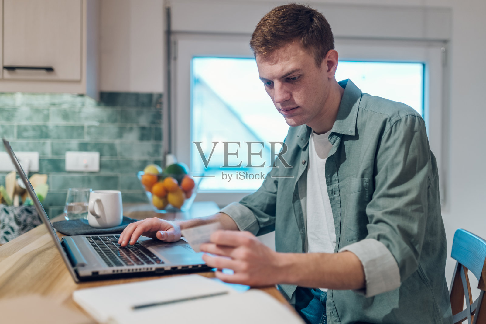 红发男人在家用笔记本电脑和信用卡照片摄影图片
