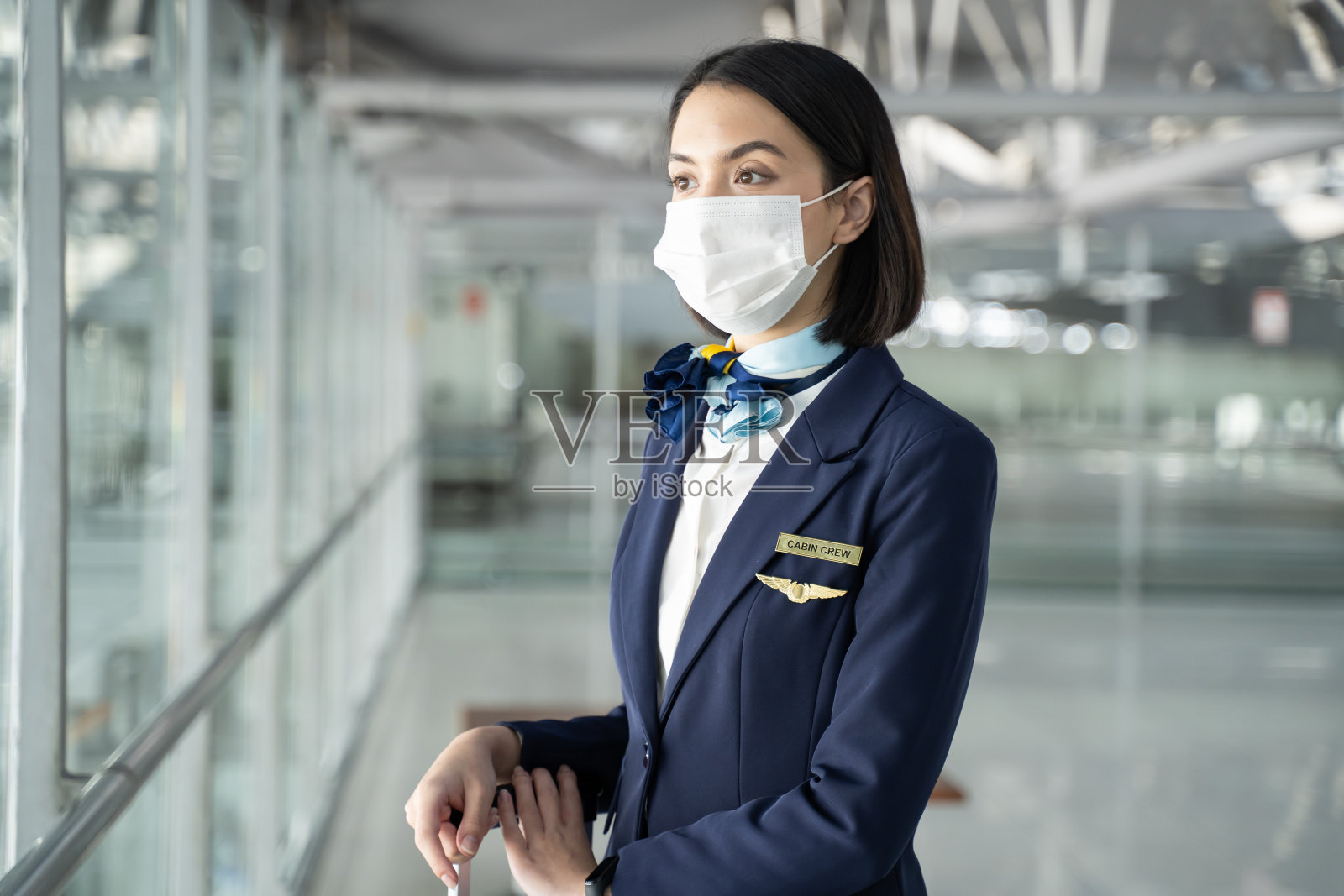 白人空乘人员站在机场候机楼的肖像。在新型冠状病毒感染症(covid - 19病毒)疫情期间，戴着口罩的漂亮空姐或乘务员正准备在飞机上工作。照片摄影图片