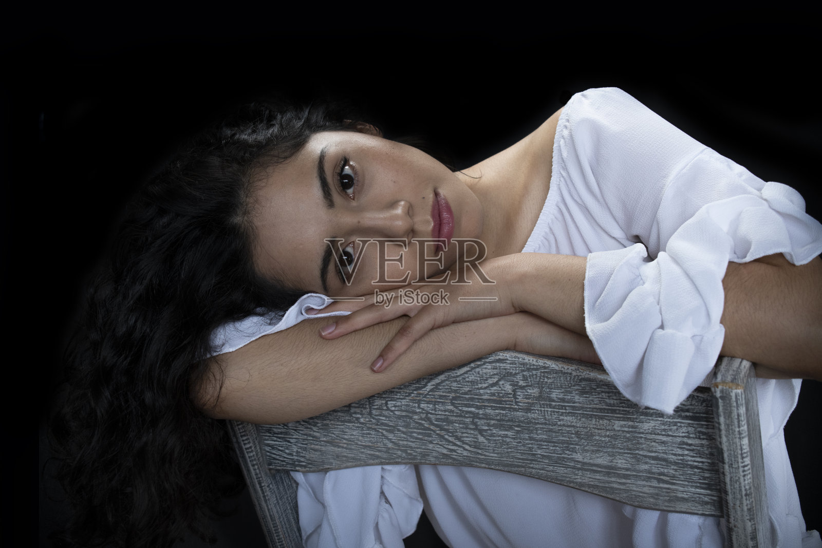 一个年轻的女人在一个黑暗的房间里靠在椅背上休息，度假照片摄影图片