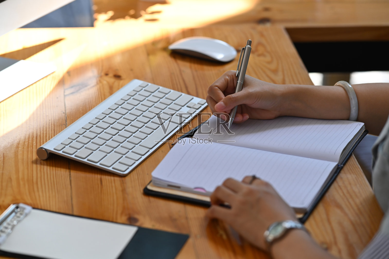 剪裁镜头女商人工作与电脑和写在笔记本上的商业计划。照片摄影图片