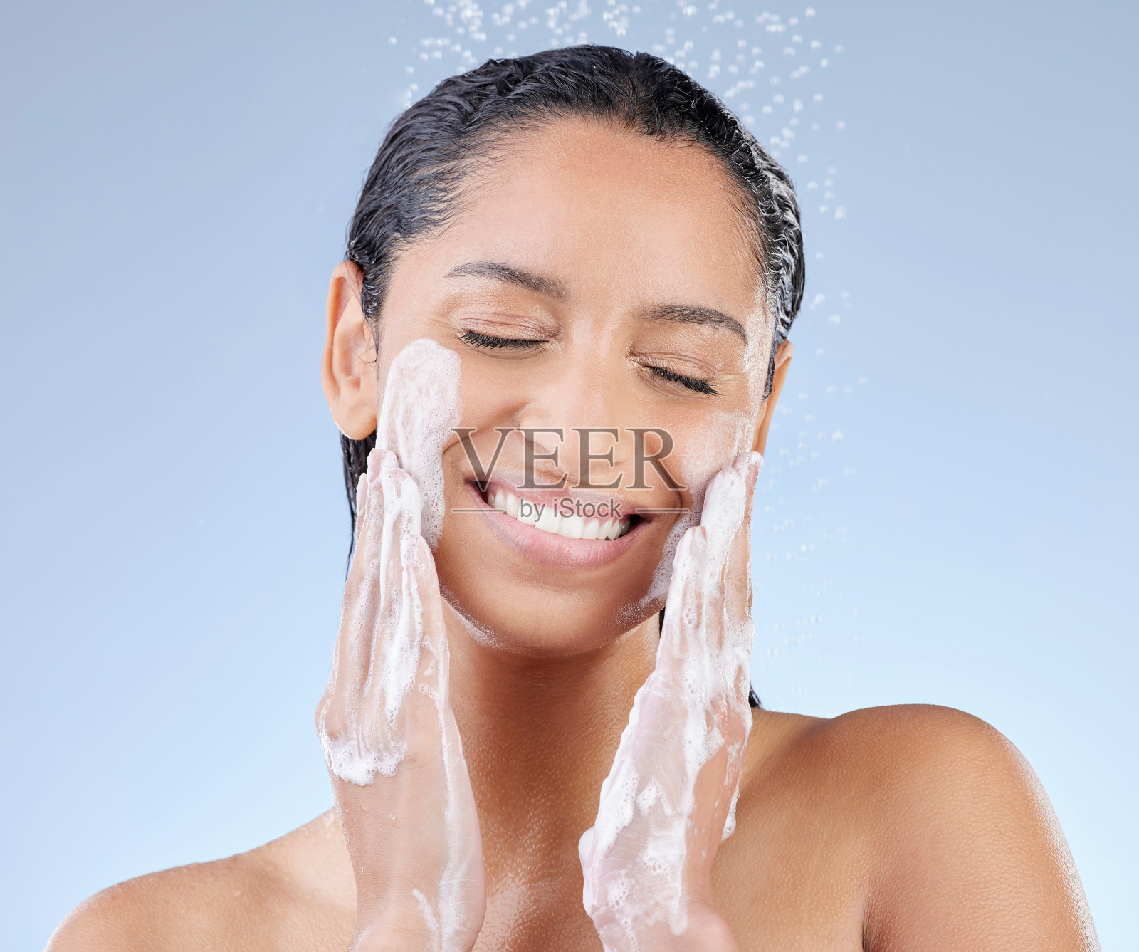 工作室拍摄的一个迷人的年轻女子在蓝色的背景下洗澡照片摄影图片