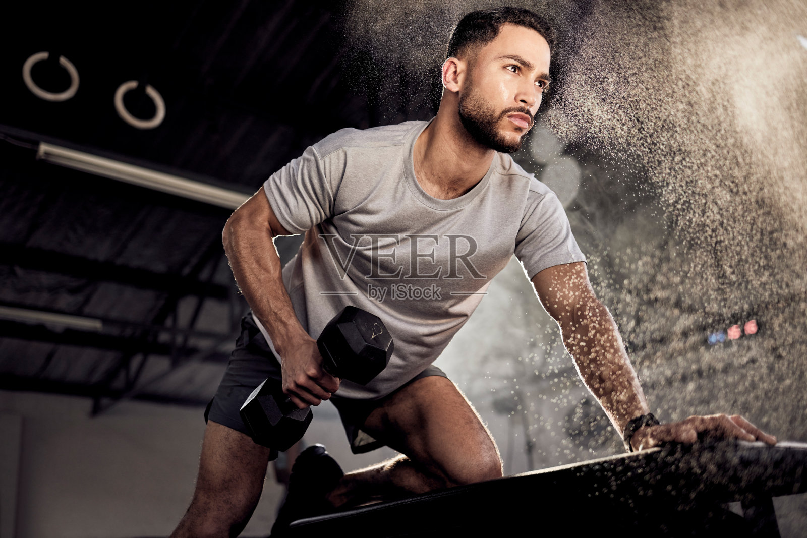 一个肌肉发达的年轻人在健身房用哑铃锻炼照片摄影图片