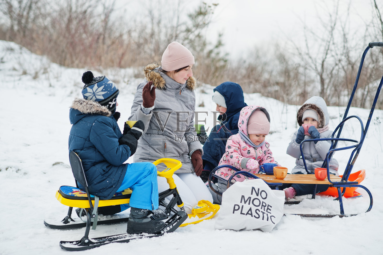 冬天，一家人在户外玩雪橇，孩子们在玩耍，喝茶。照片摄影图片
