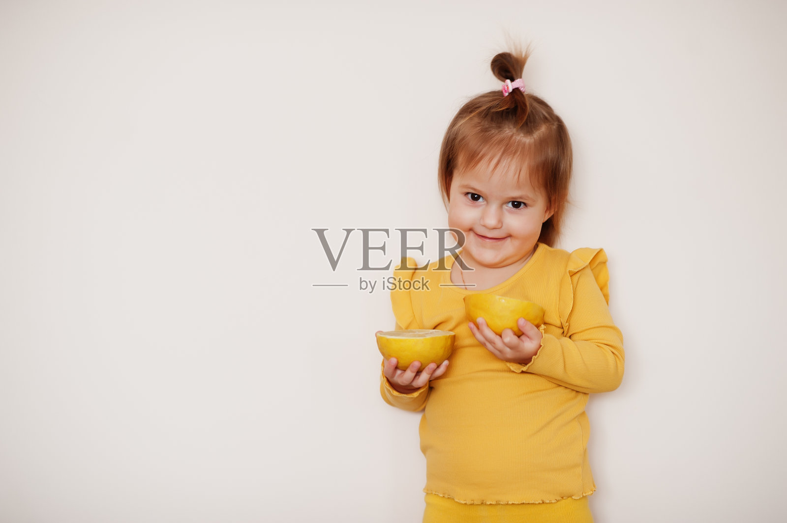 小女孩在黄色与柠檬，孤立的背景。照片摄影图片