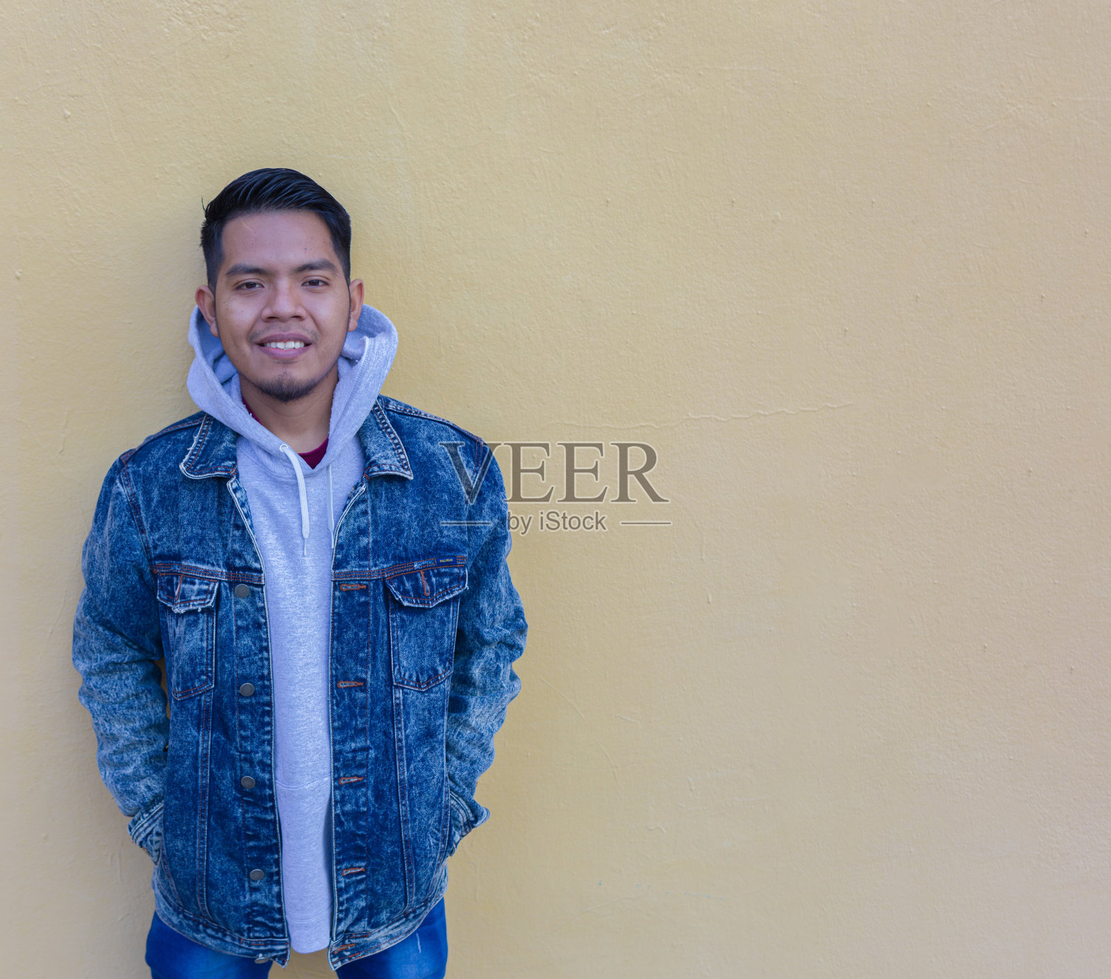 一个墨西哥人微笑着看着黄色墙壁前的镜头照片摄影图片