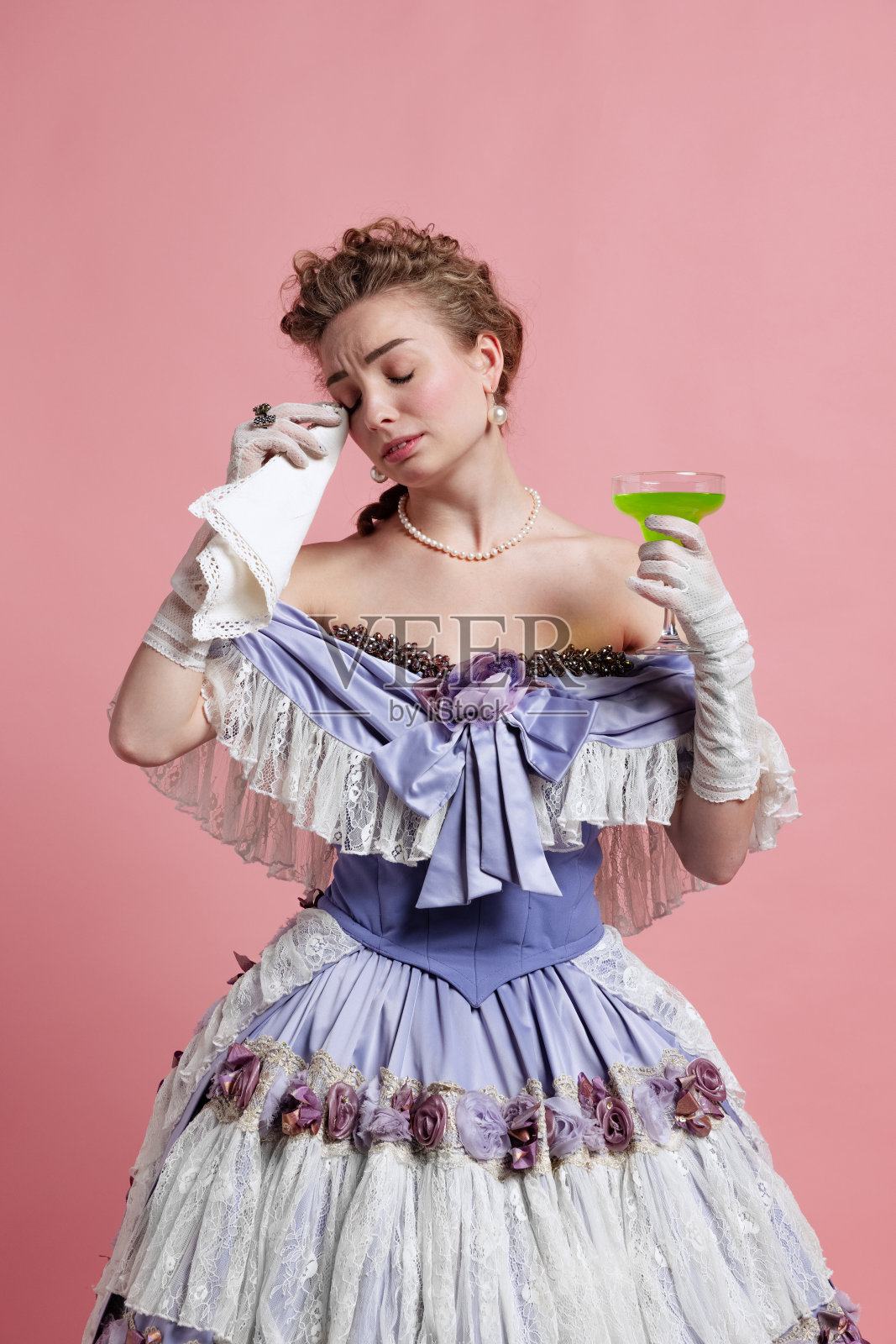 悲伤。年轻可爱的女孩在中世纪的形象在文艺复兴风格的服装孤立在粉红色的背景。年代比较，美照片摄影图片